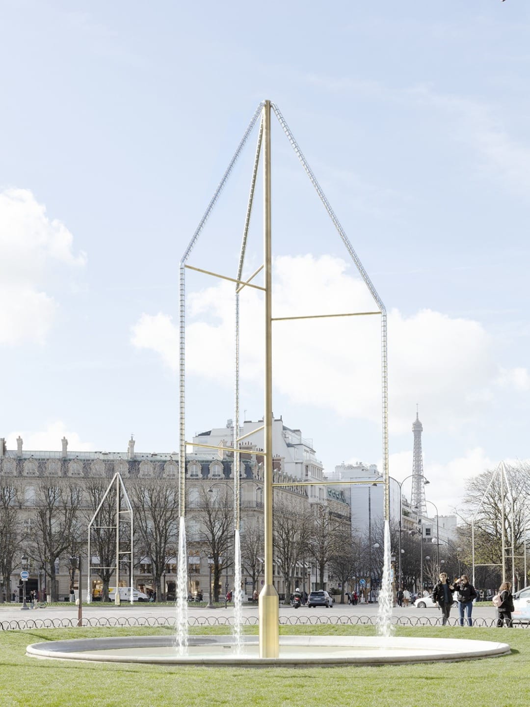 Art installation of a tall, geometric metal structure with a Parisian cityscape and Eiffel Tower in the background
