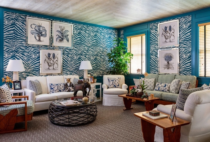 Stylish living room with zebra print wallpaper, white sofas, plants, and vibrant artwork on the walls.