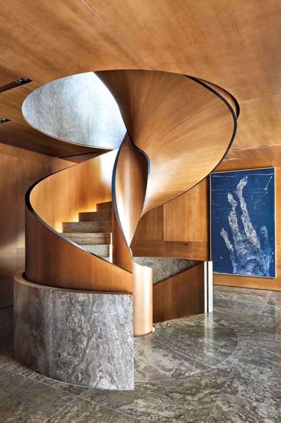 Spiral staircase with wood and stone elements in a modern interior, featuring a blue artwork on the wall.