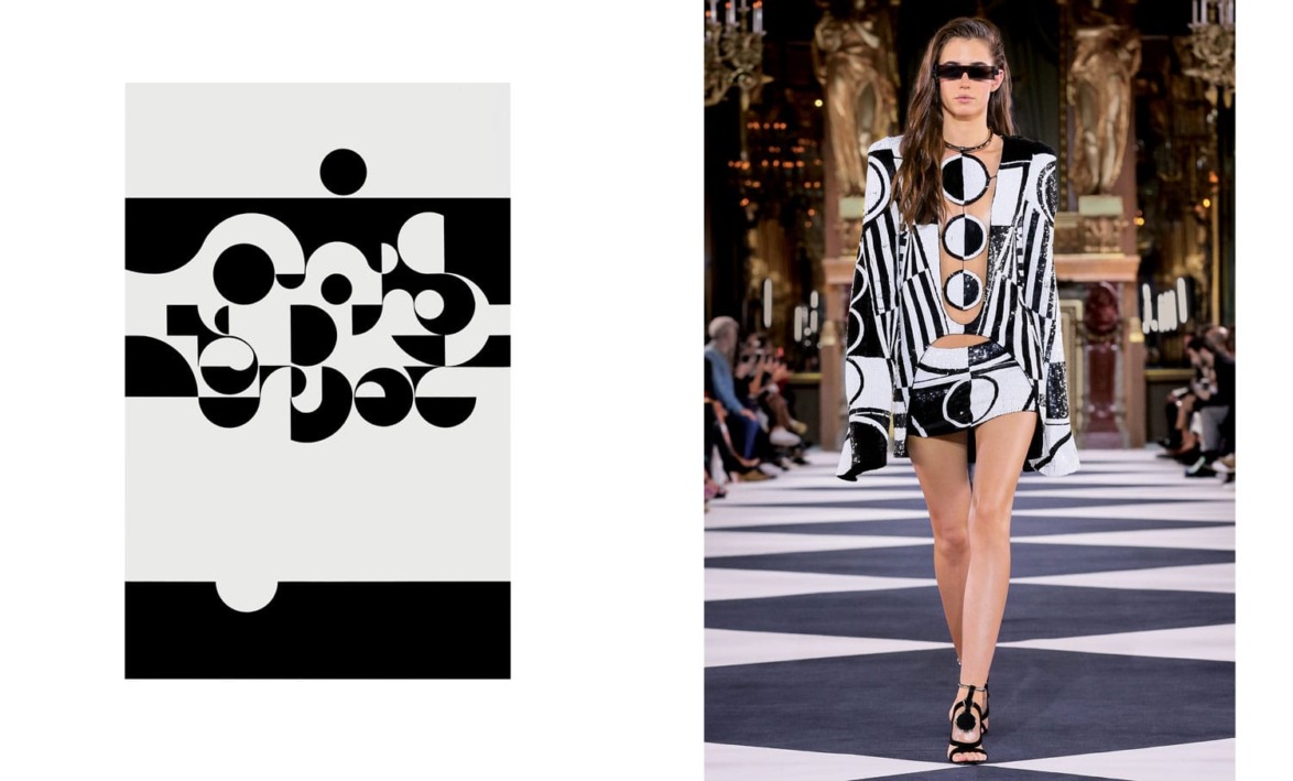 Model walks runway in bold black and white geometric outfit and sunglasses at fashion show.