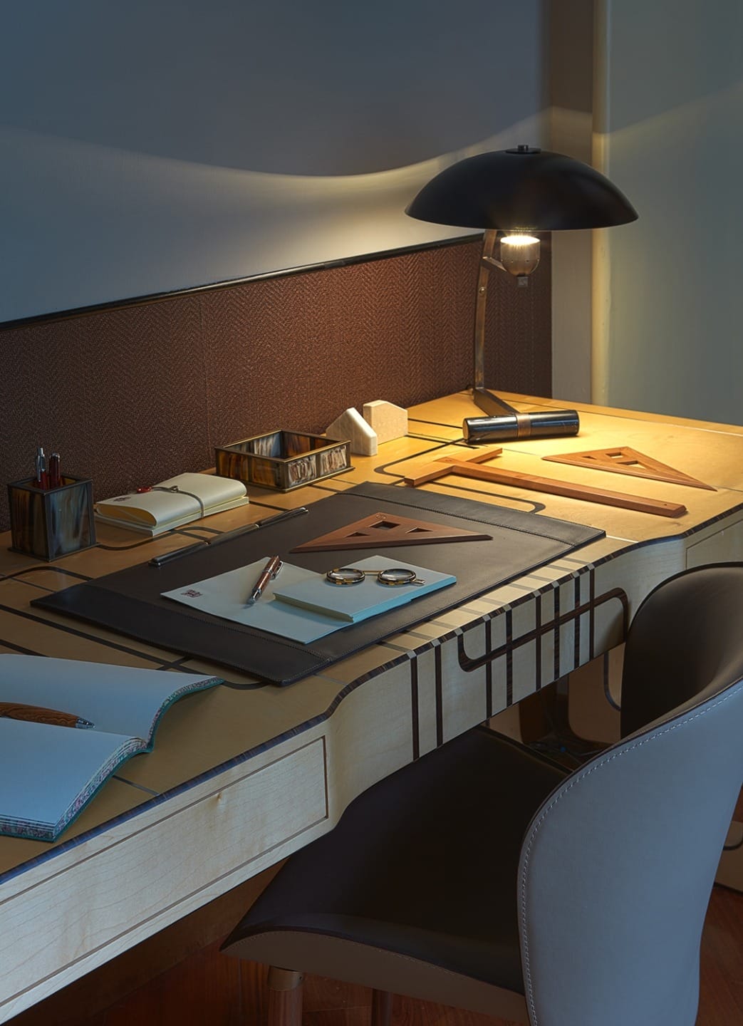 Modern desk with lamp, notebooks, and geometric tools, set against a warm, cozy ambiance.