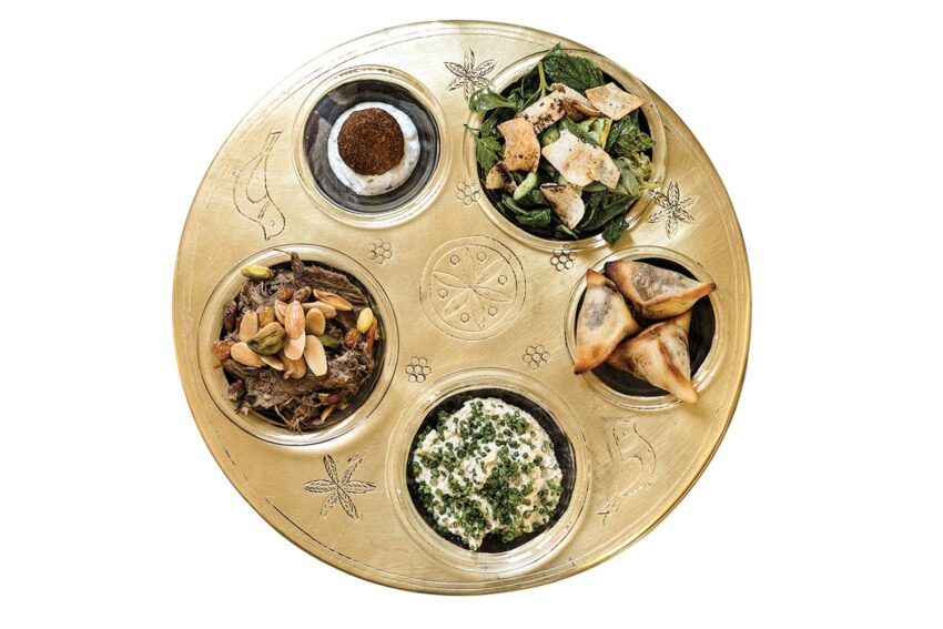 A round platter with five Middle Eastern dishes including salad, pastries, and dip, elegantly arranged on a decorative tray.