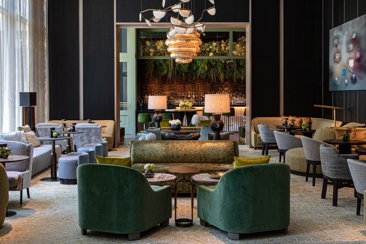 Luxurious hotel lounge with stylish seating, elegant chandeliers, and a vibrant bar adorned with lush greenery.