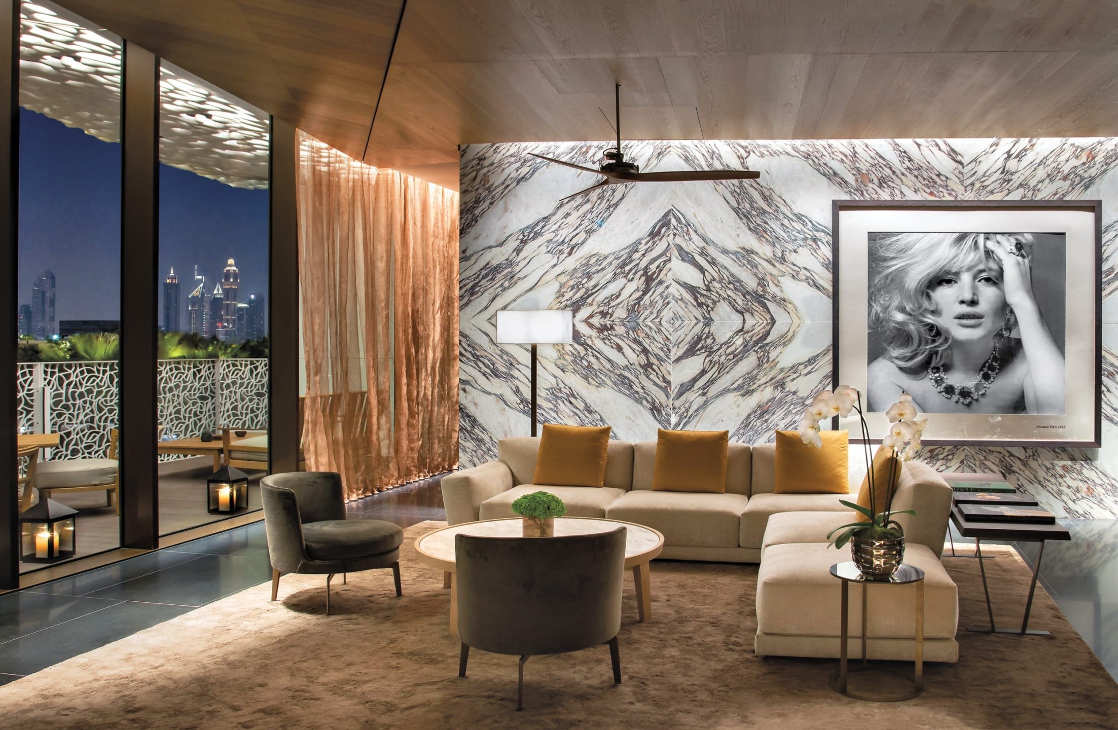 Luxurious modern living room with elegant furniture, stylish decor, marble accents, and a city view from a balcony.