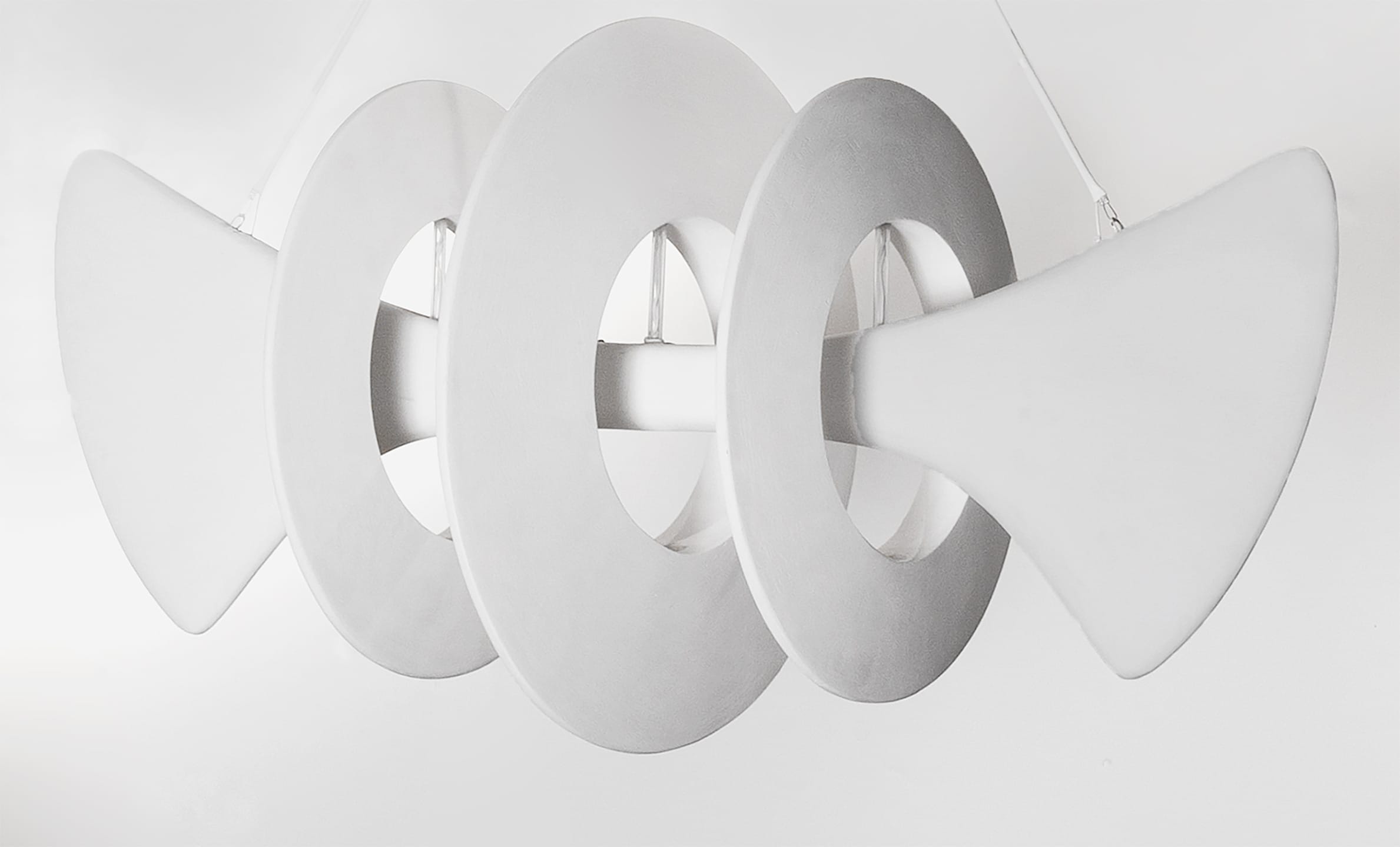 Modern white abstract sculpture with circular and triangular shapes suspended from the ceiling in a minimalist space