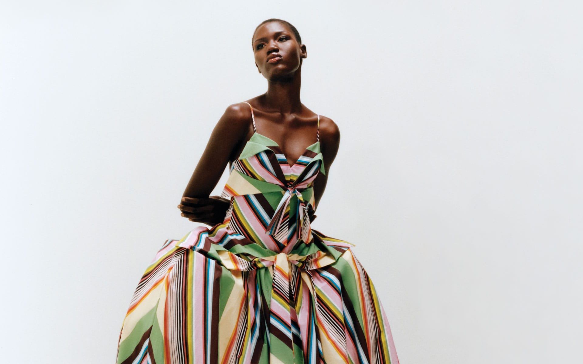 Person wearing a colorful striped dress standing against a white background.