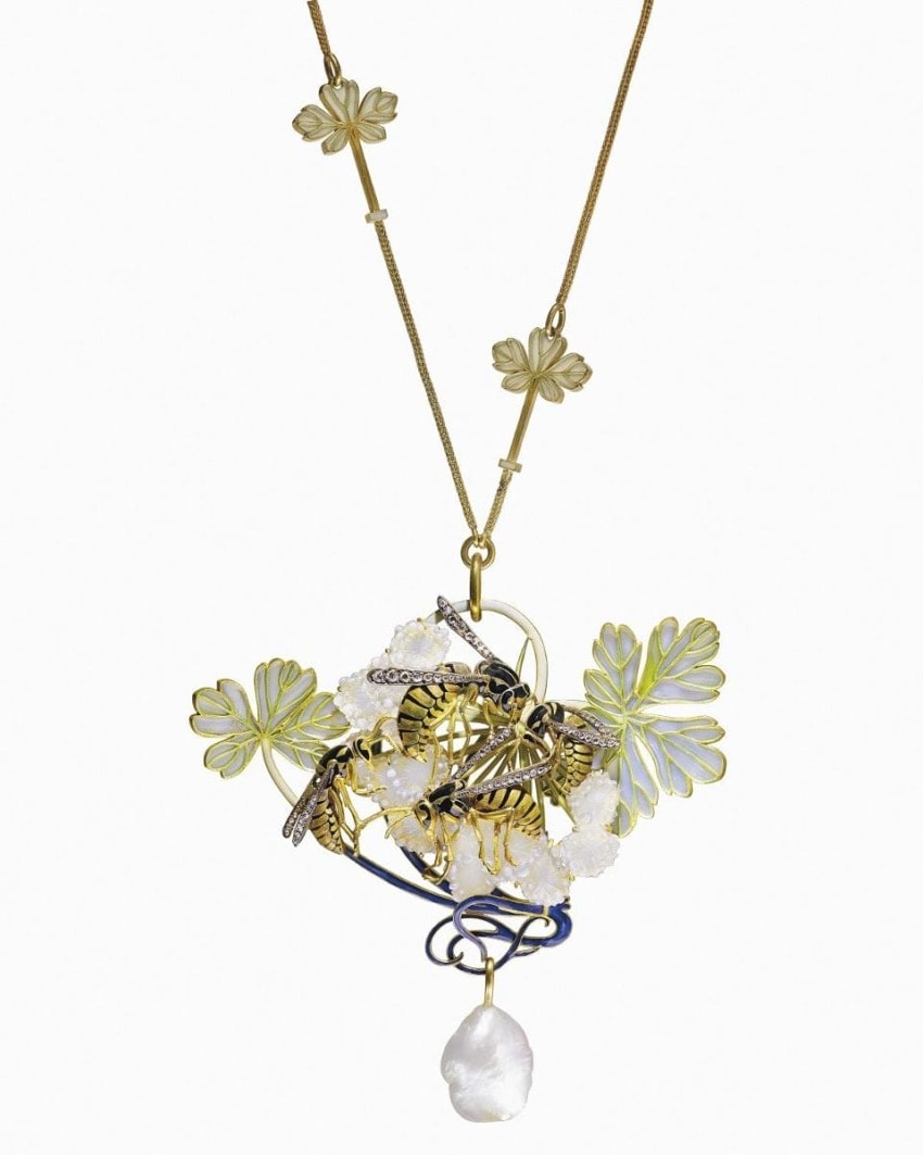 Artistic necklace with intricate floral designs, pearls, and a teardrop pendant on a gold chain.