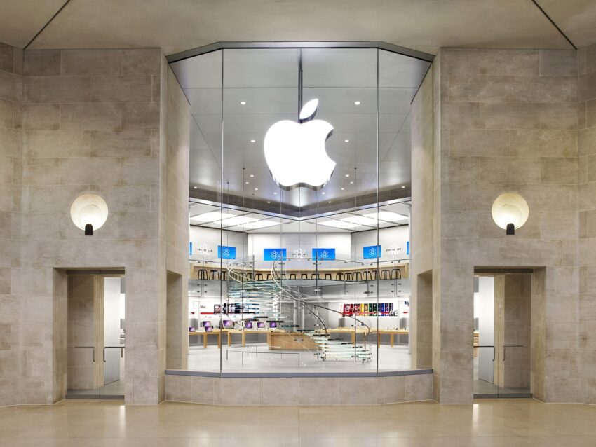 Exterior view of an Apple Store with large glass entrance and prominent Apple logo above.