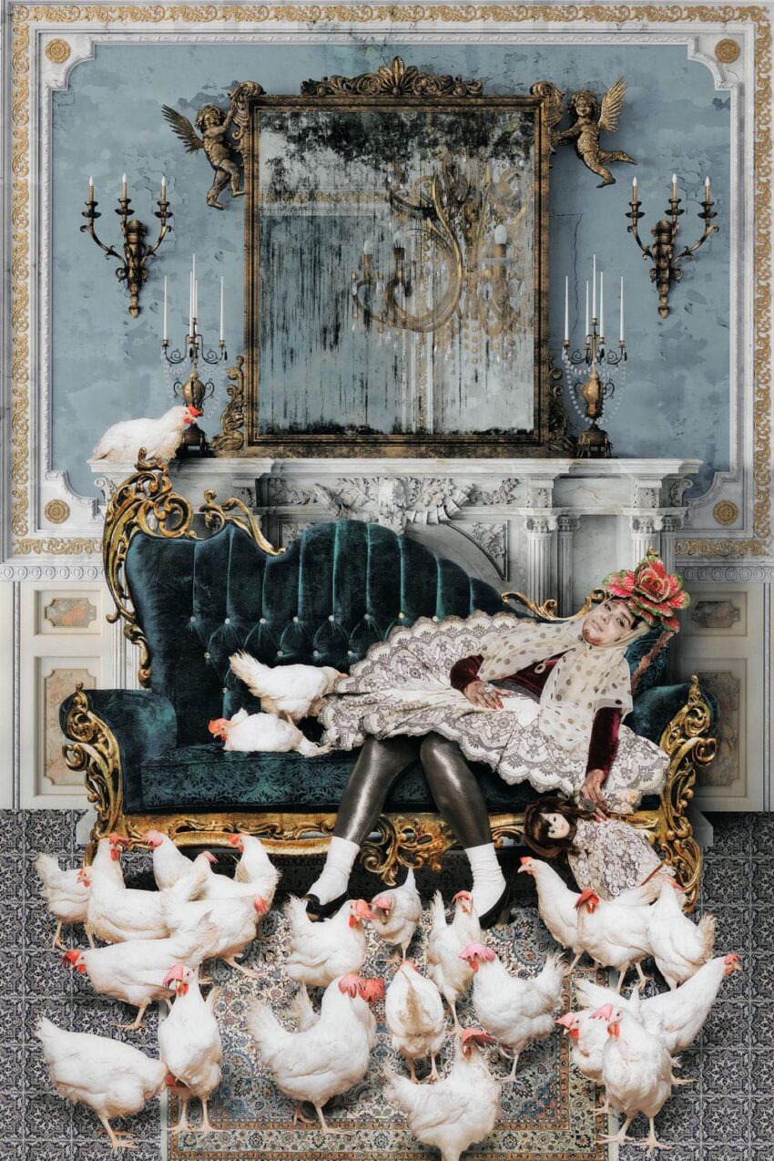Person in royal attire asleep on a vintage sofa surrounded by white chickens in an ornate room with mirror and chandeliers.