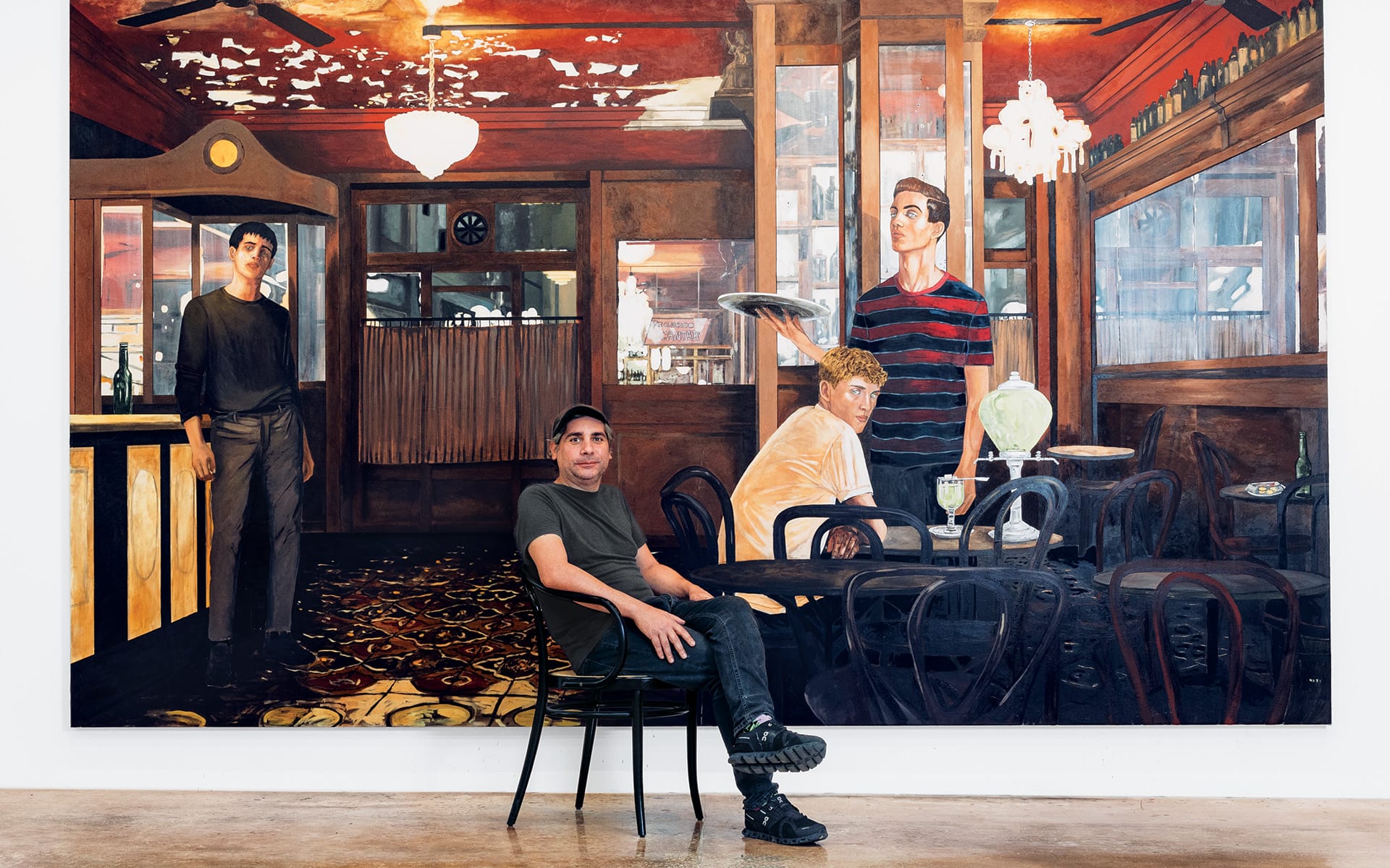 Person sitting in front of a large painting depicting a restaurant scene with figures in a dimly lit interior.