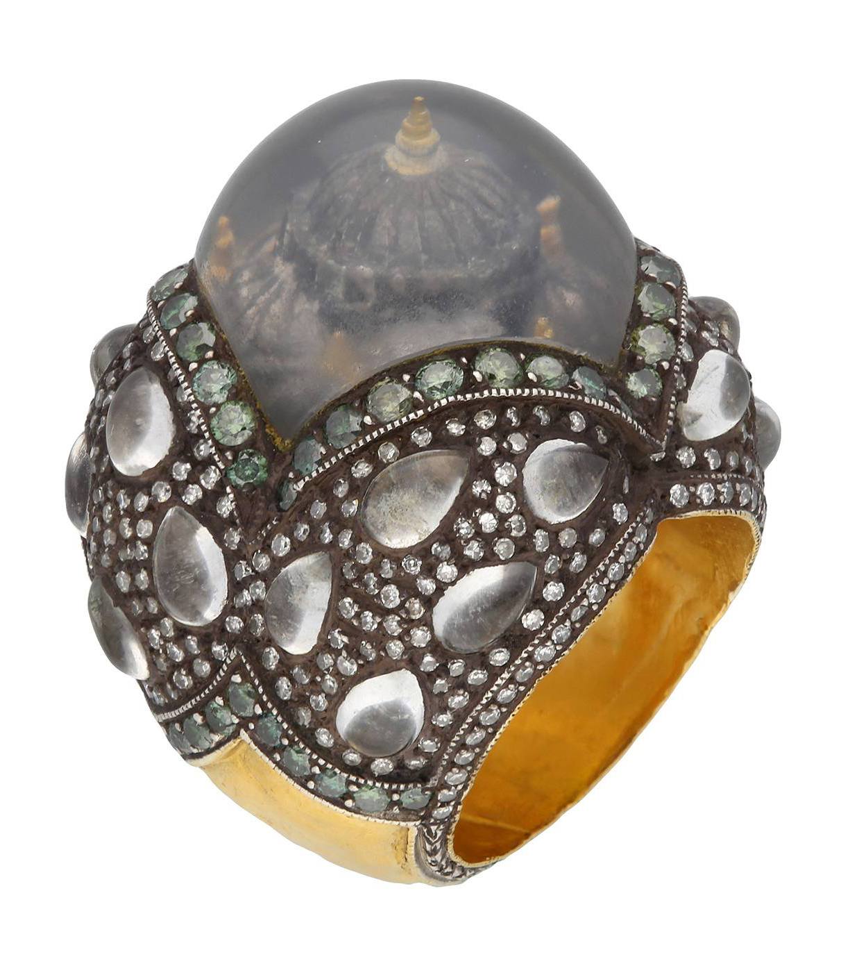 Ornate silver ring with green gemstones and a large domed crystal featuring a miniature architectural design inside.