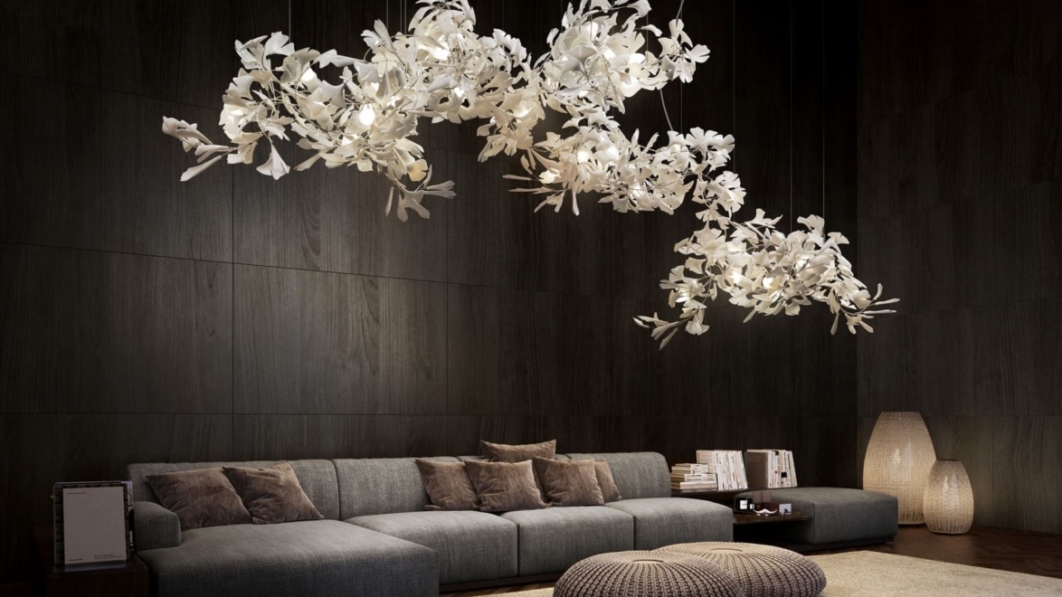 Modern living room with dark wood walls, gray sectional sofa, white floral chandeliers, wicker poufs, and soft lighting.