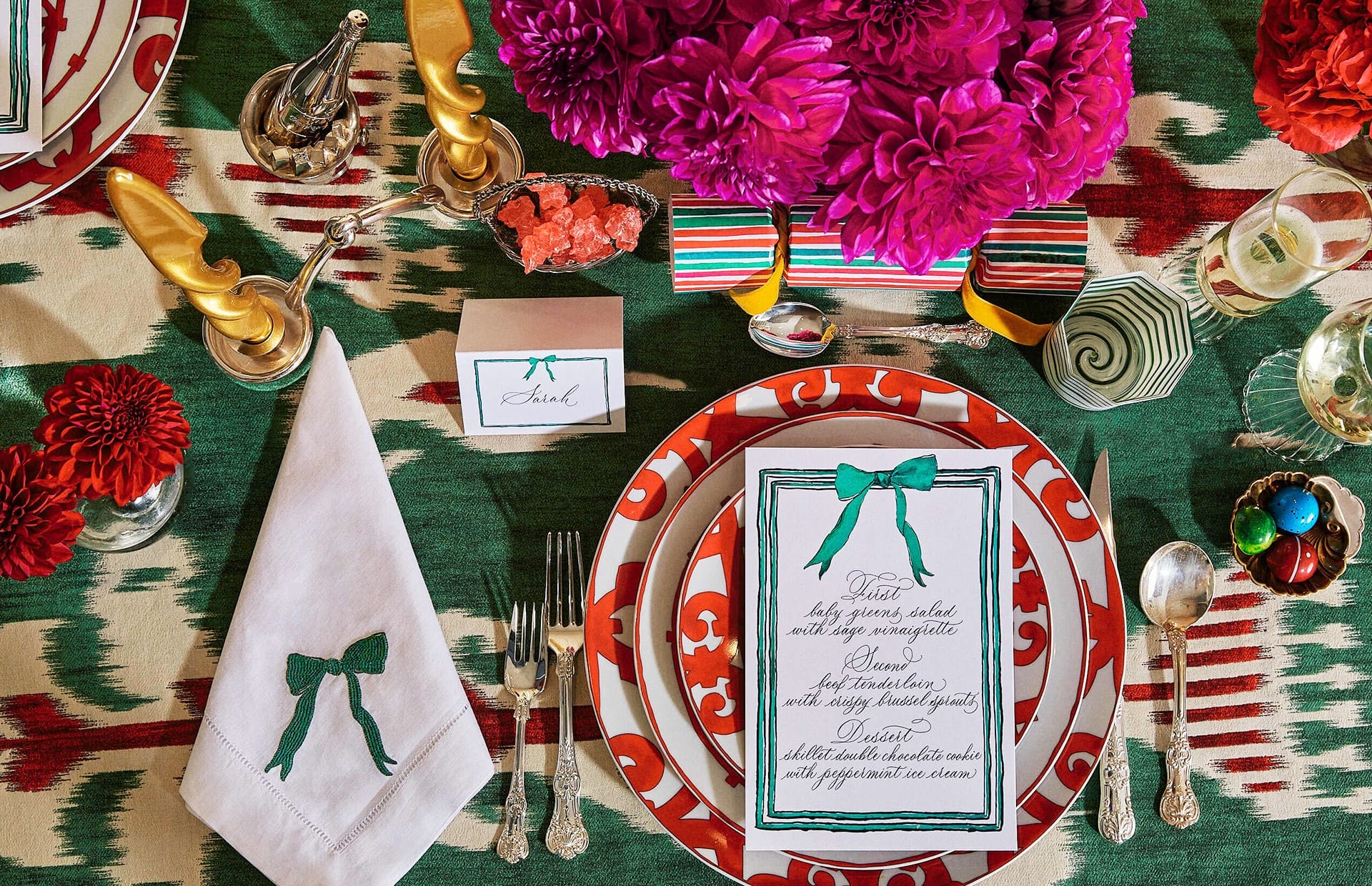 Colorful, elegant table setting with floral centerpiece, patterned plates, silverware, and a detailed menu in the center.