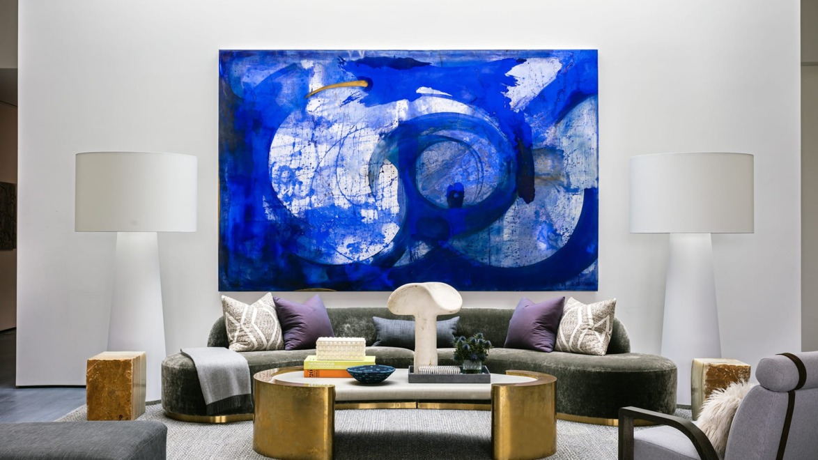 Modern living room with large blue abstract painting, elegant furniture, and decorative accents.