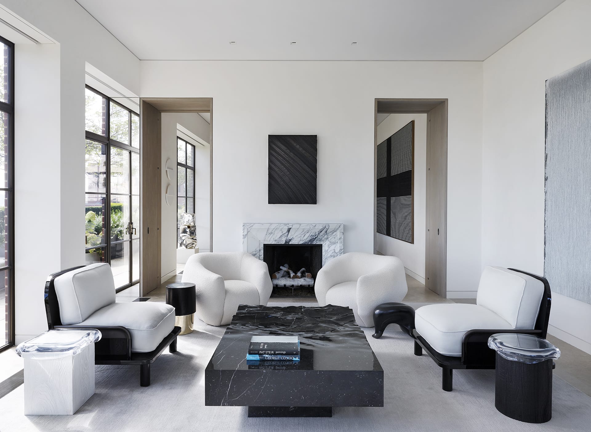 Modern living room with white armchairs, black marble coffee table, and abstract wall art near large windows.