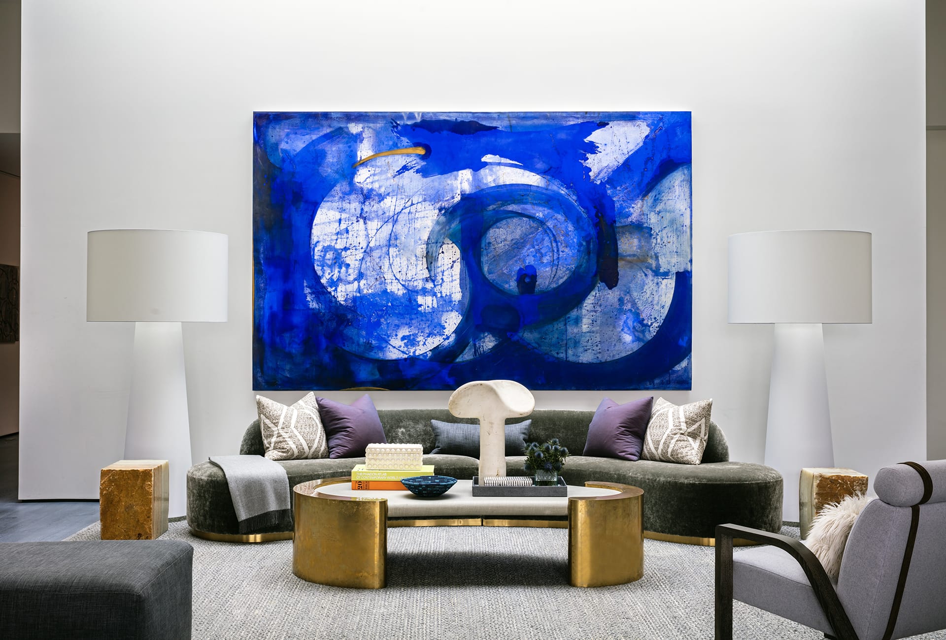 Modern living room with large blue abstract painting, elegant furniture, and decorative accents.