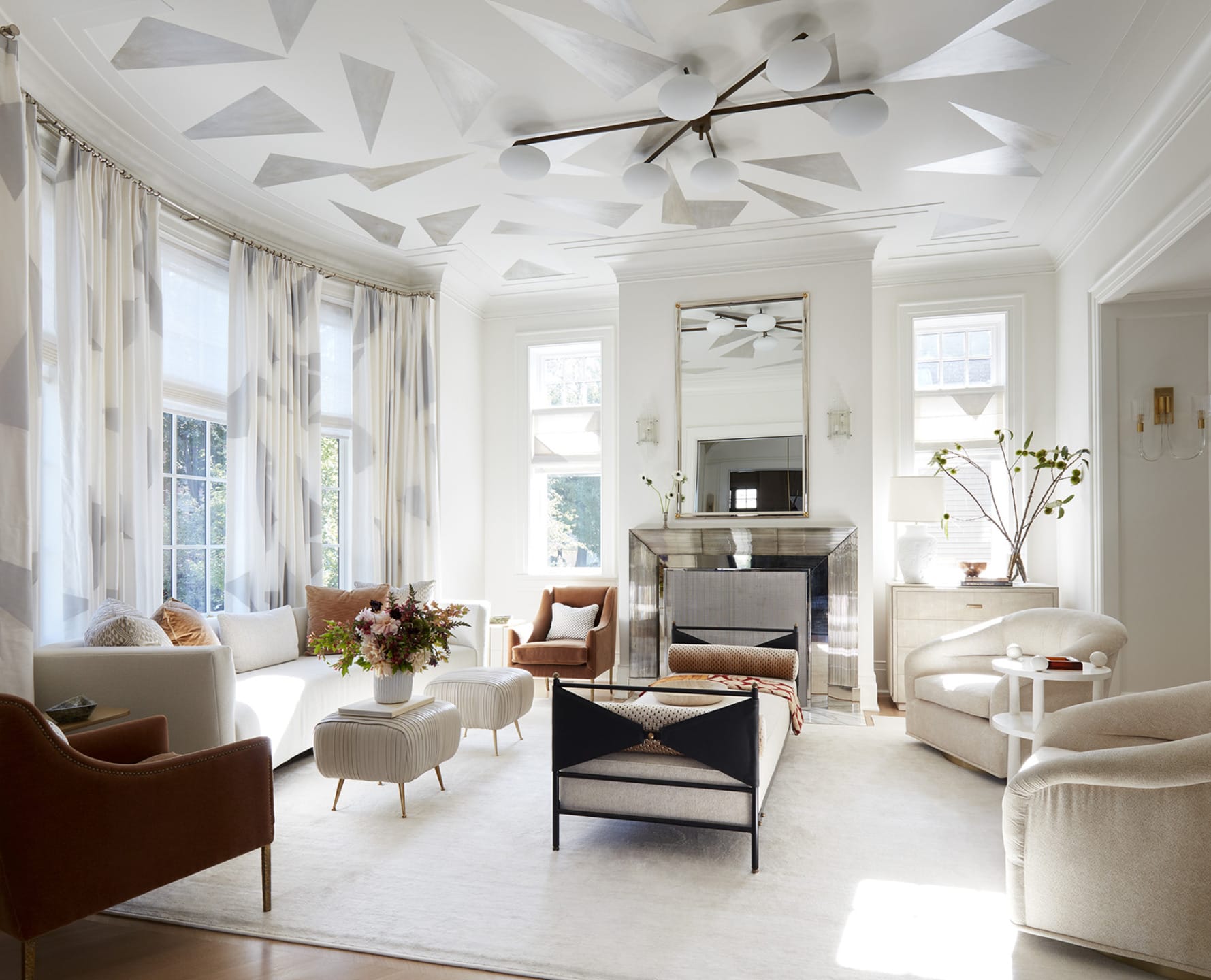 Elegant living room with modern decor, white walls, patterned ceiling, large windows, comfortable seating, and a central coffee table.