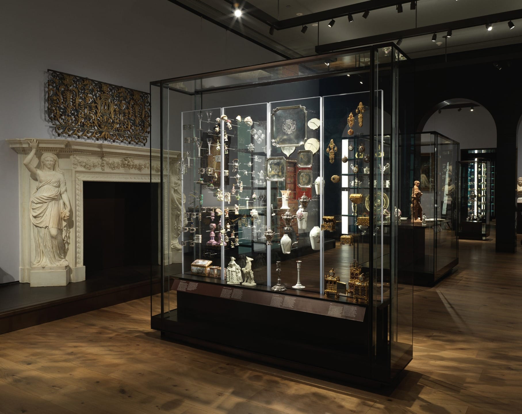 Museum exhibit with a variety of artifacts displayed in a glass case, including sculptures and decorative art pieces.