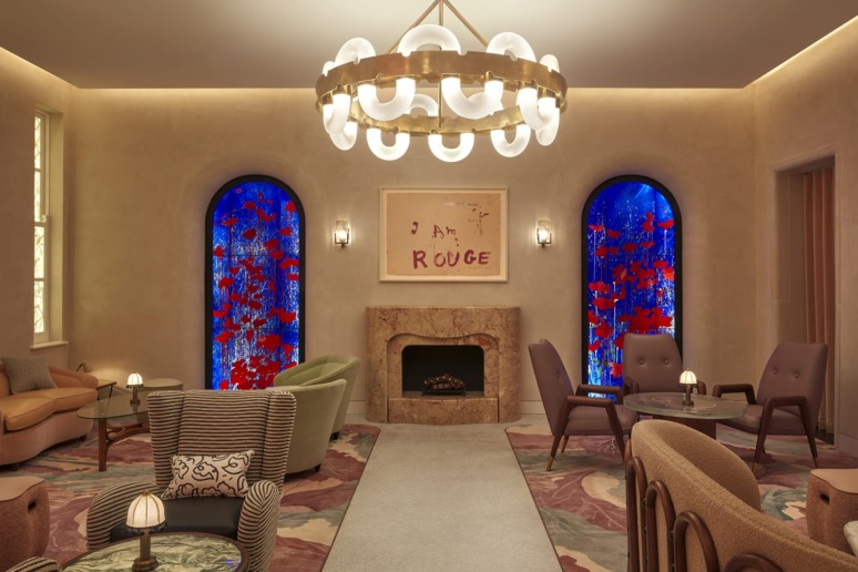 Elegant lounge with modern chandelier, stained glass windows, and comfortable seating around a marble fireplace.