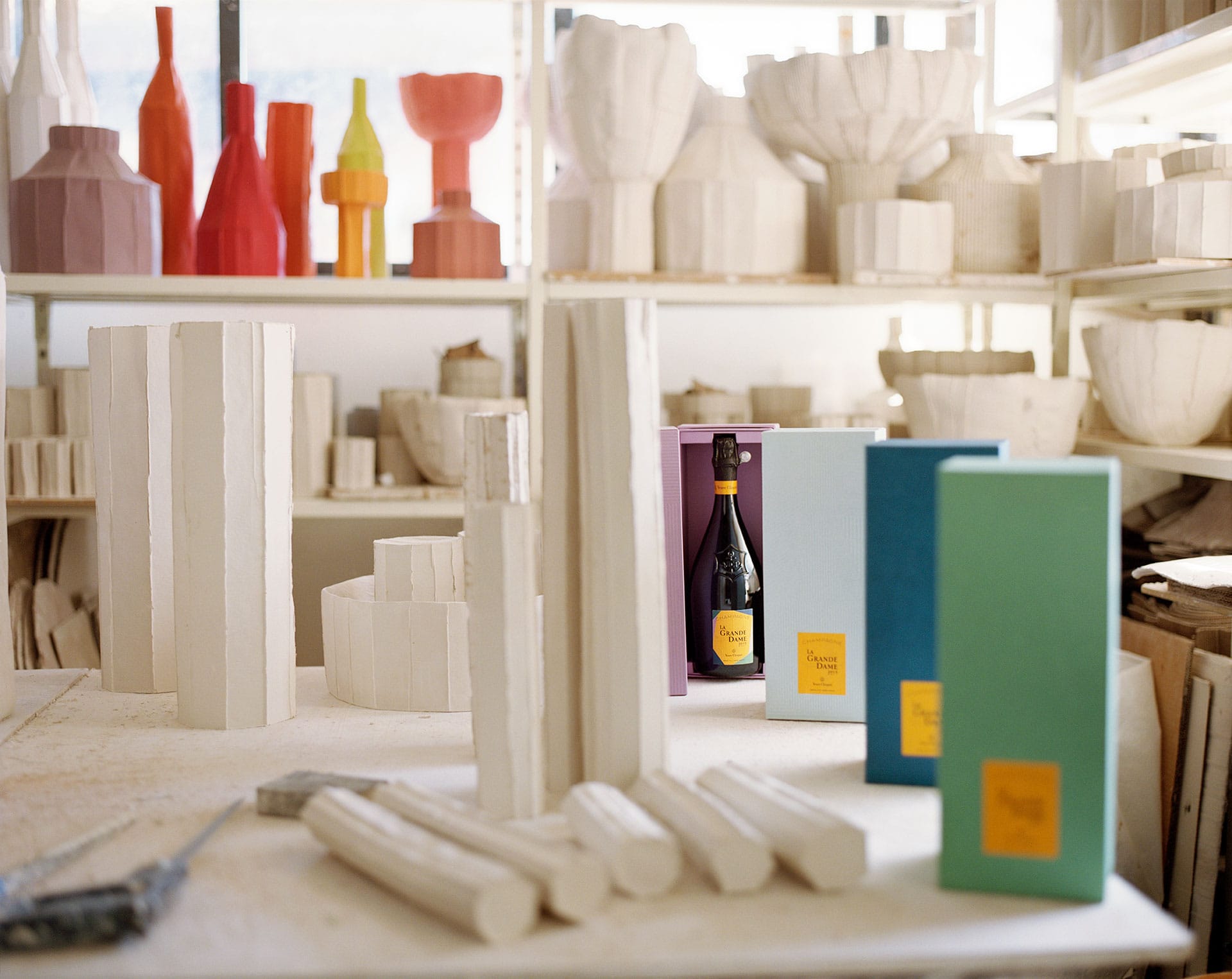 Art studio with plaster sculptures and colorful bottles in the background, displaying a warm creative atmosphere.