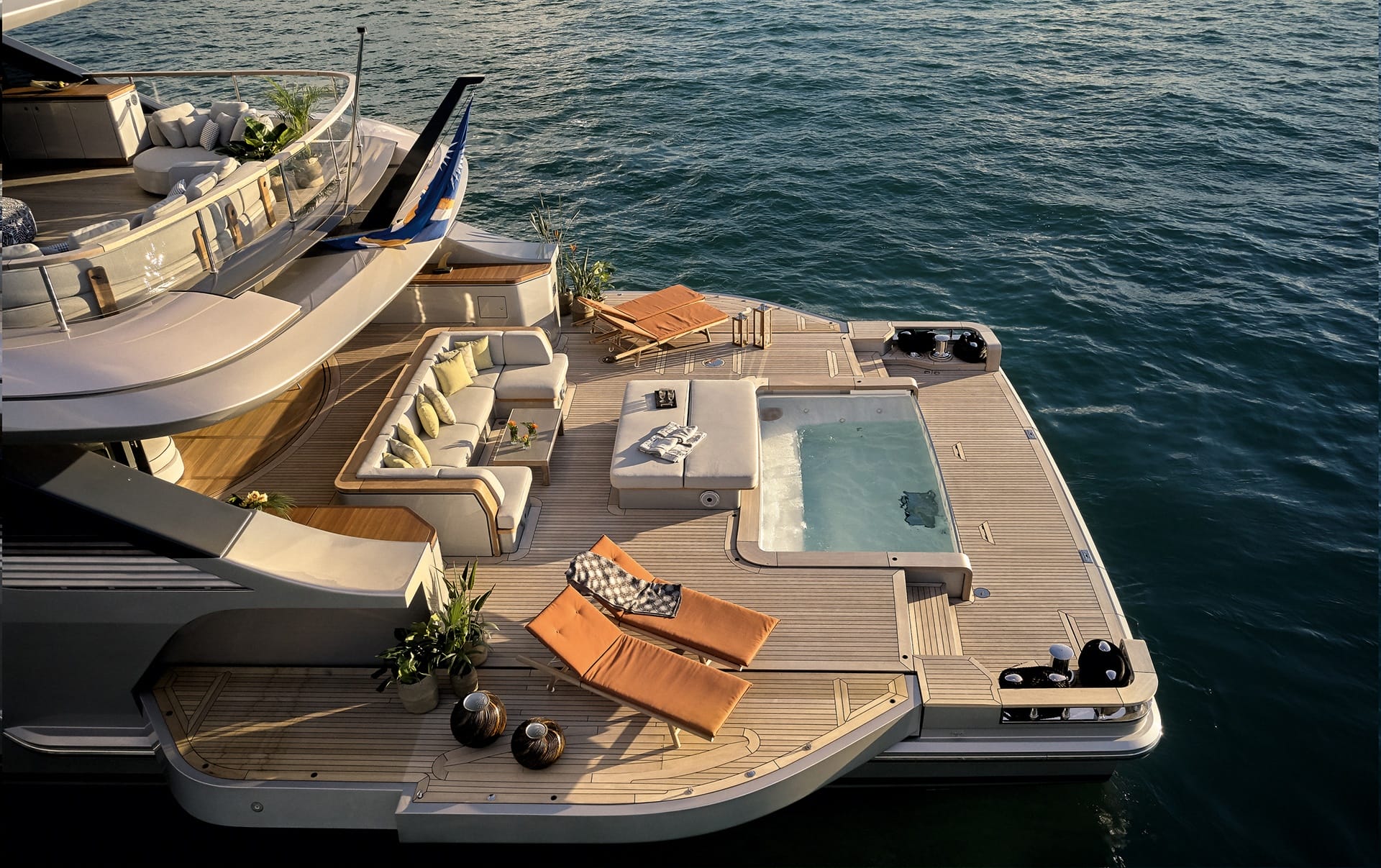 Luxury yacht deck with outdoor seating, hot tub, and lounge chairs overlooking calm ocean waters at sunset.