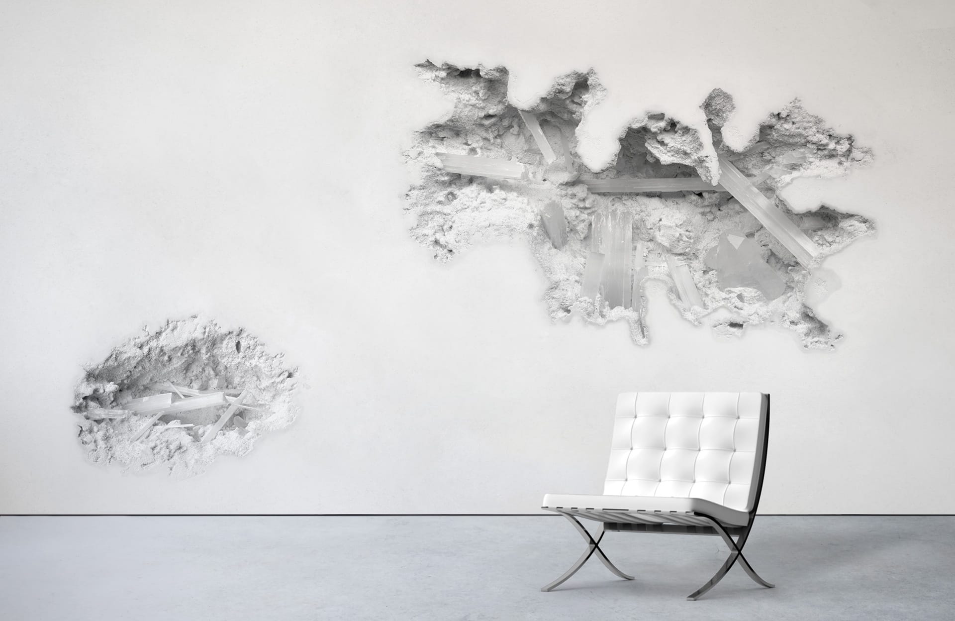 White chair on a concrete floor with a modern art installation of fragmented wall sections in the background.