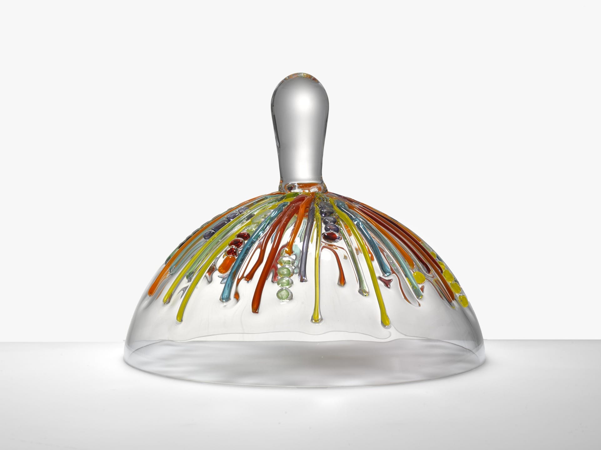 Glass dome with colorful raised, flowing patterns and a clear handle on top against a neutral background.