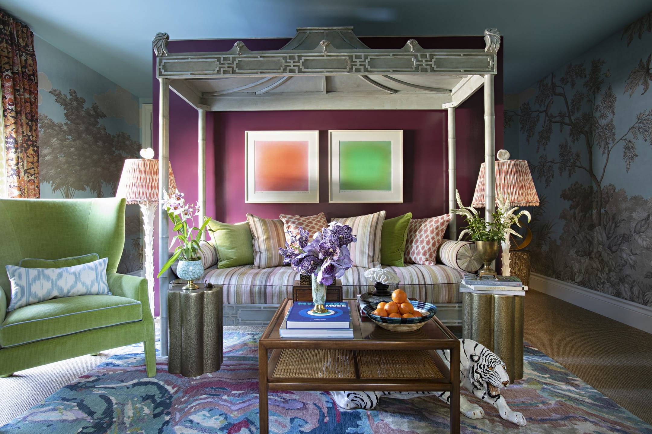 Eclectic living room with a canopy daybed, colorful cushions, vibrant rug, green armchair, and decorative lamps.