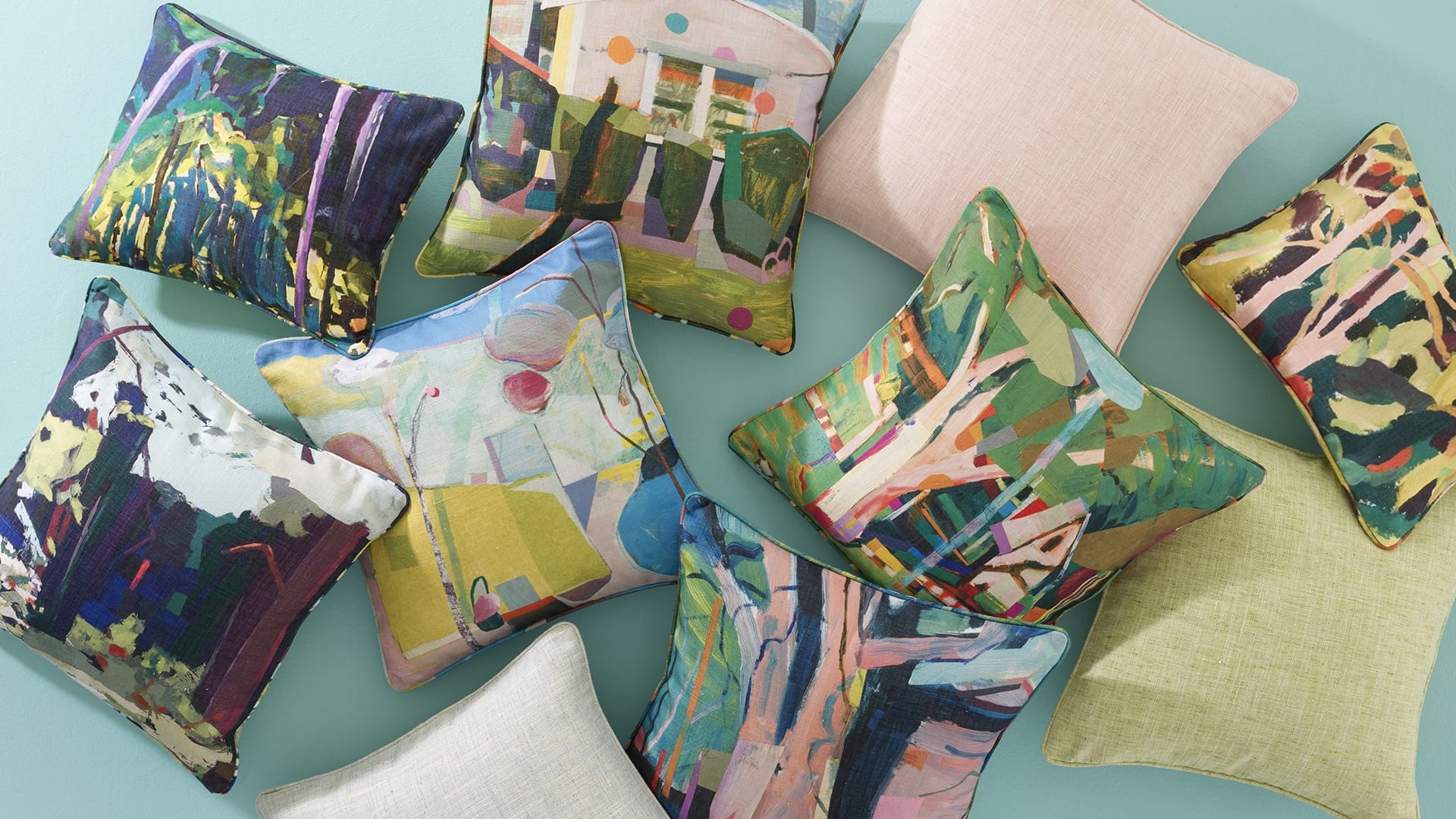 Colorful throw pillows with abstract designs and various patterns arranged on a light blue surface.