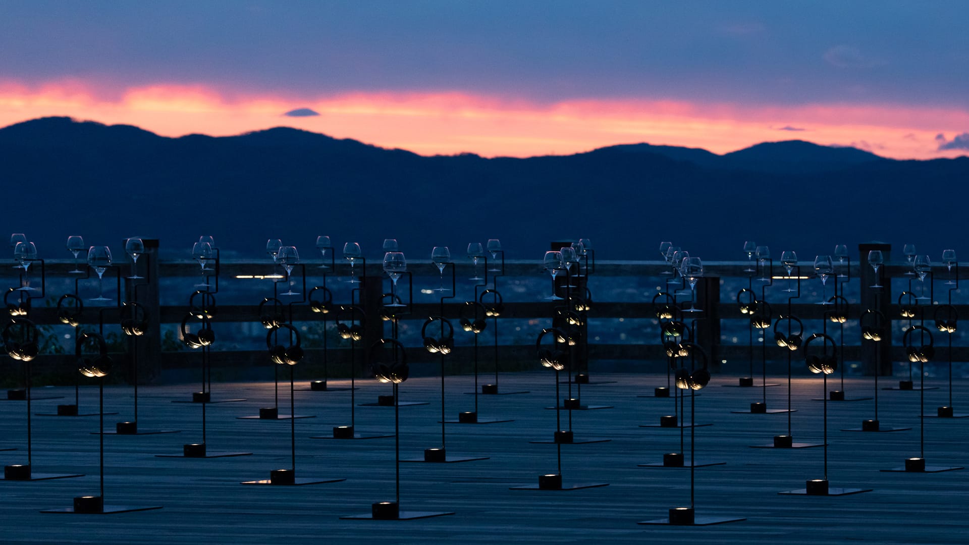 Sunset over mountains with wine glasses on stands, creating a stunning silhouette against the colorful sky.