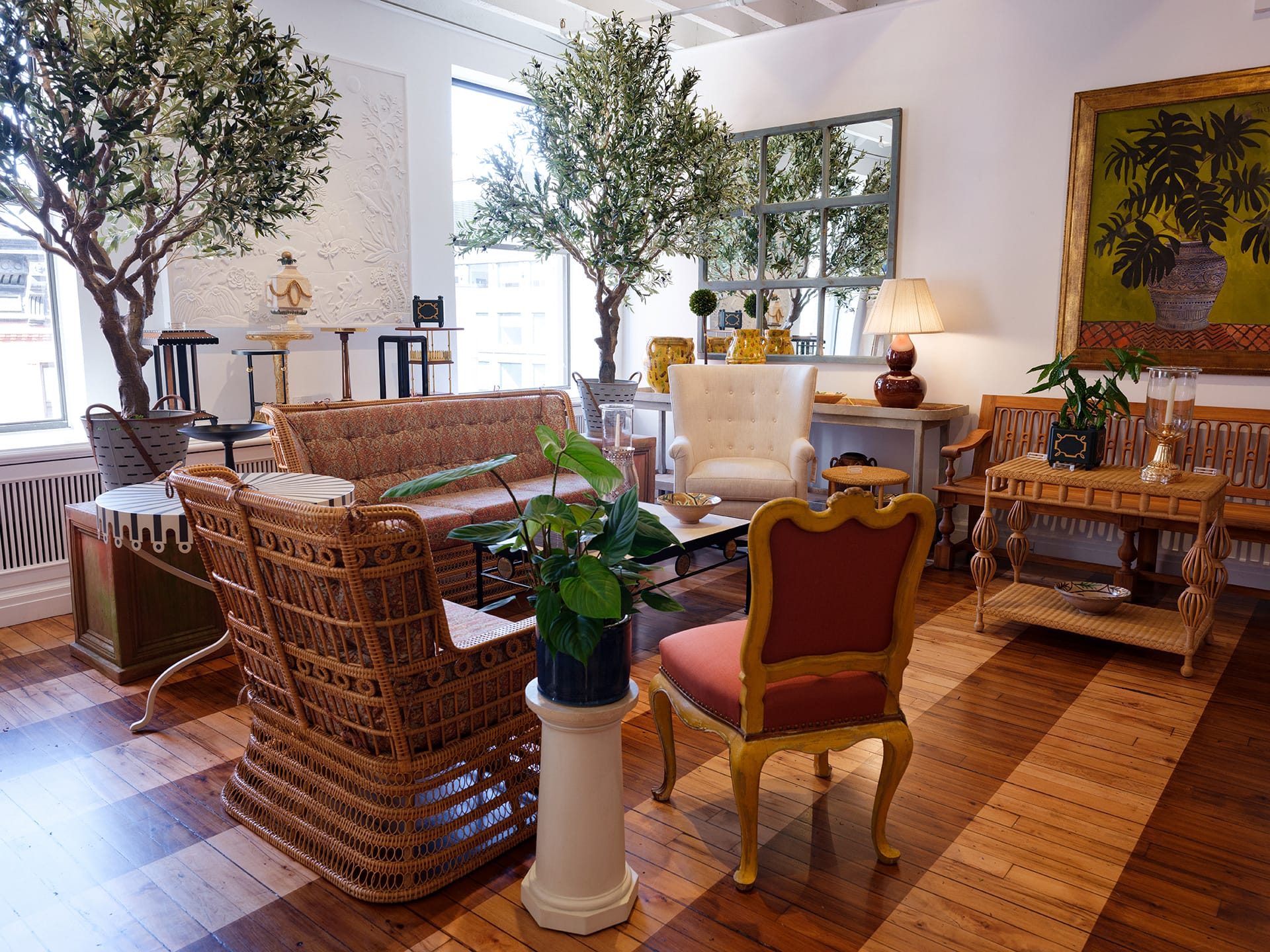 Elegant living room with wicker furniture, large potted plants, decorative wall art, and a wooden floor.
