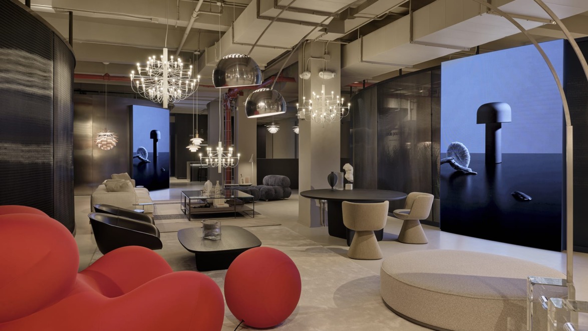 Modern showroom with contemporary furniture, red sofa, unique lighting fixtures, and digital screens showcasing product designs.