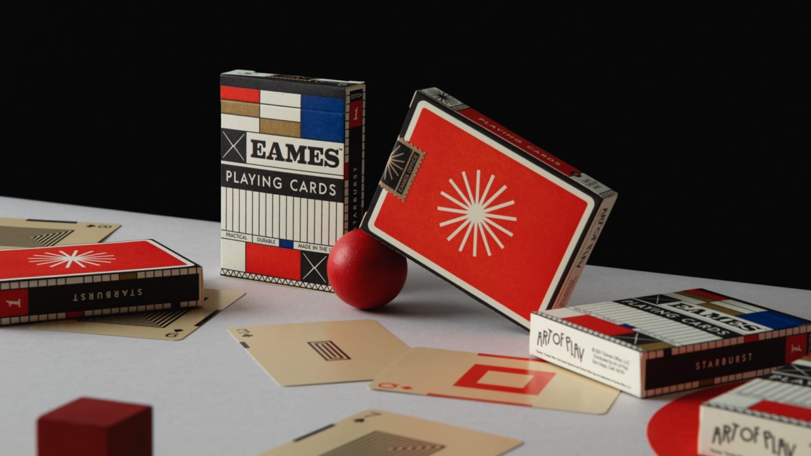 Assorted playing cards and a red sphere on a table, including open and closed card boxes with artistic designs.