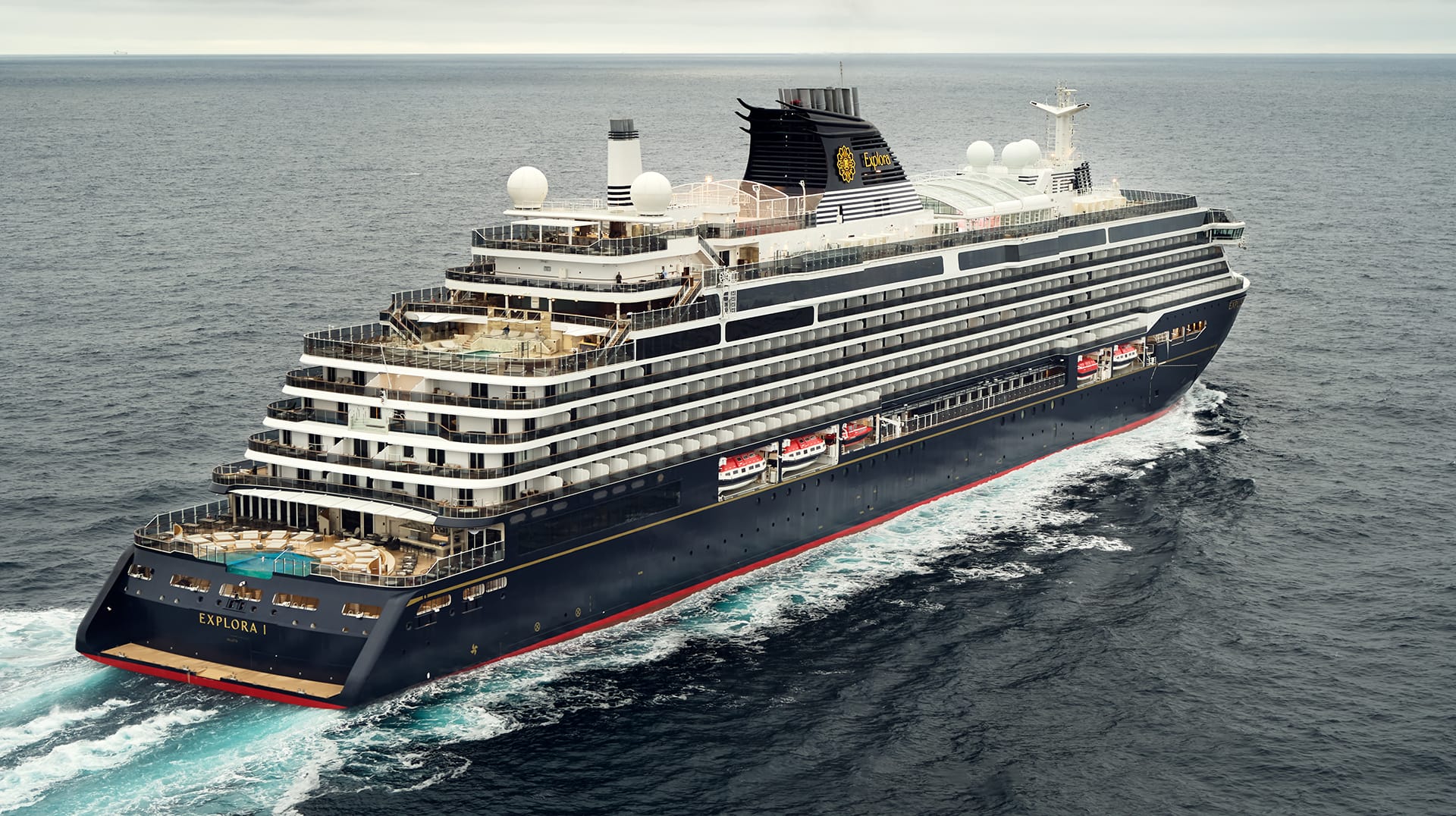 Large cruise ship named Explora sailing on open ocean with multiple decks and amenities visible.