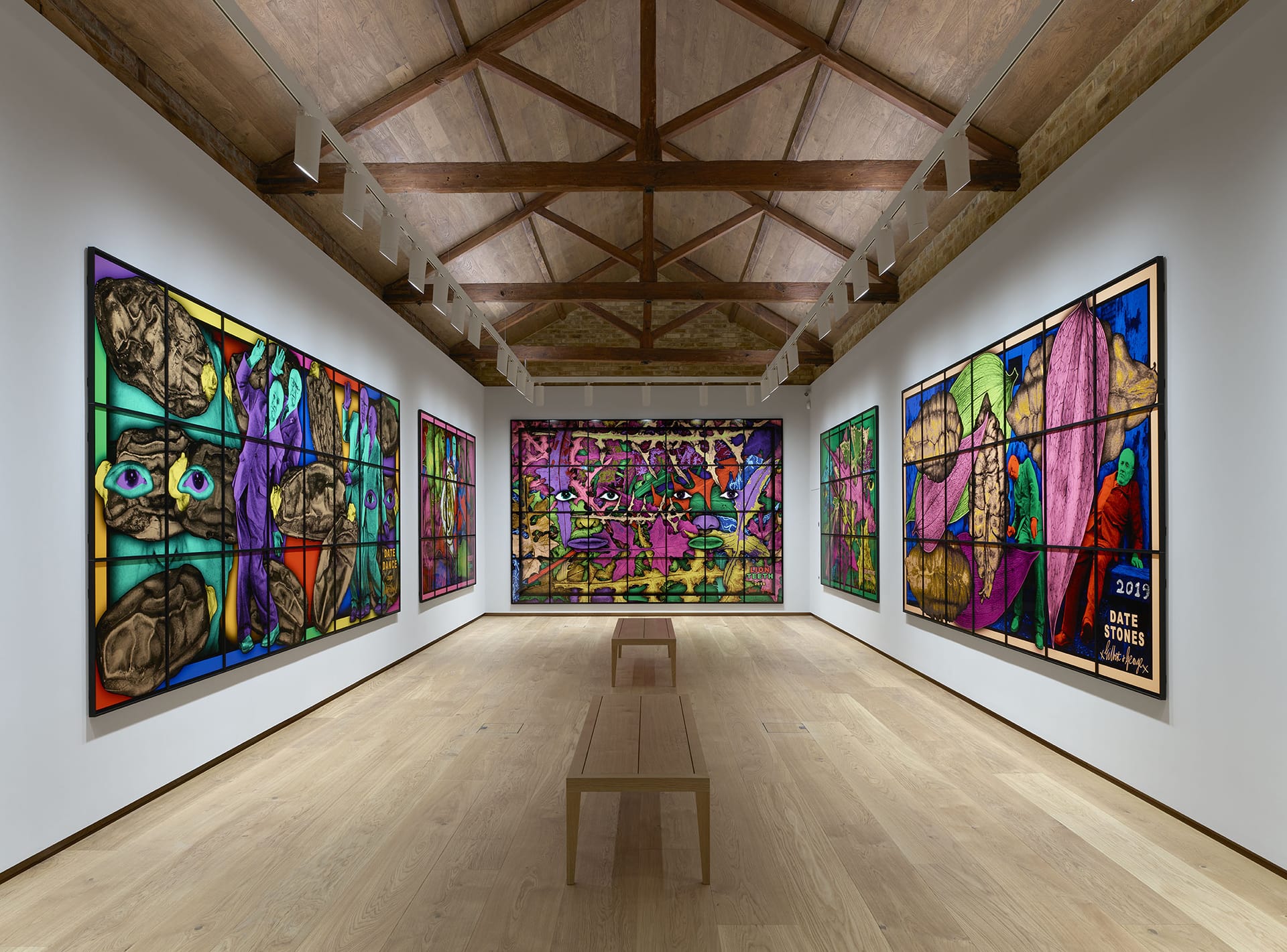 Gallery with vibrant stained glass artwork displayed on four walls, featuring abstract and colorful designs.
