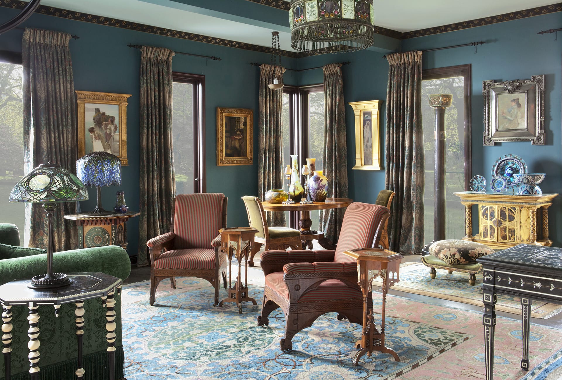 Elegant living room with vintage furniture, teal walls, ornate lighting, and artistic decor elements creating a classic atmosphere.