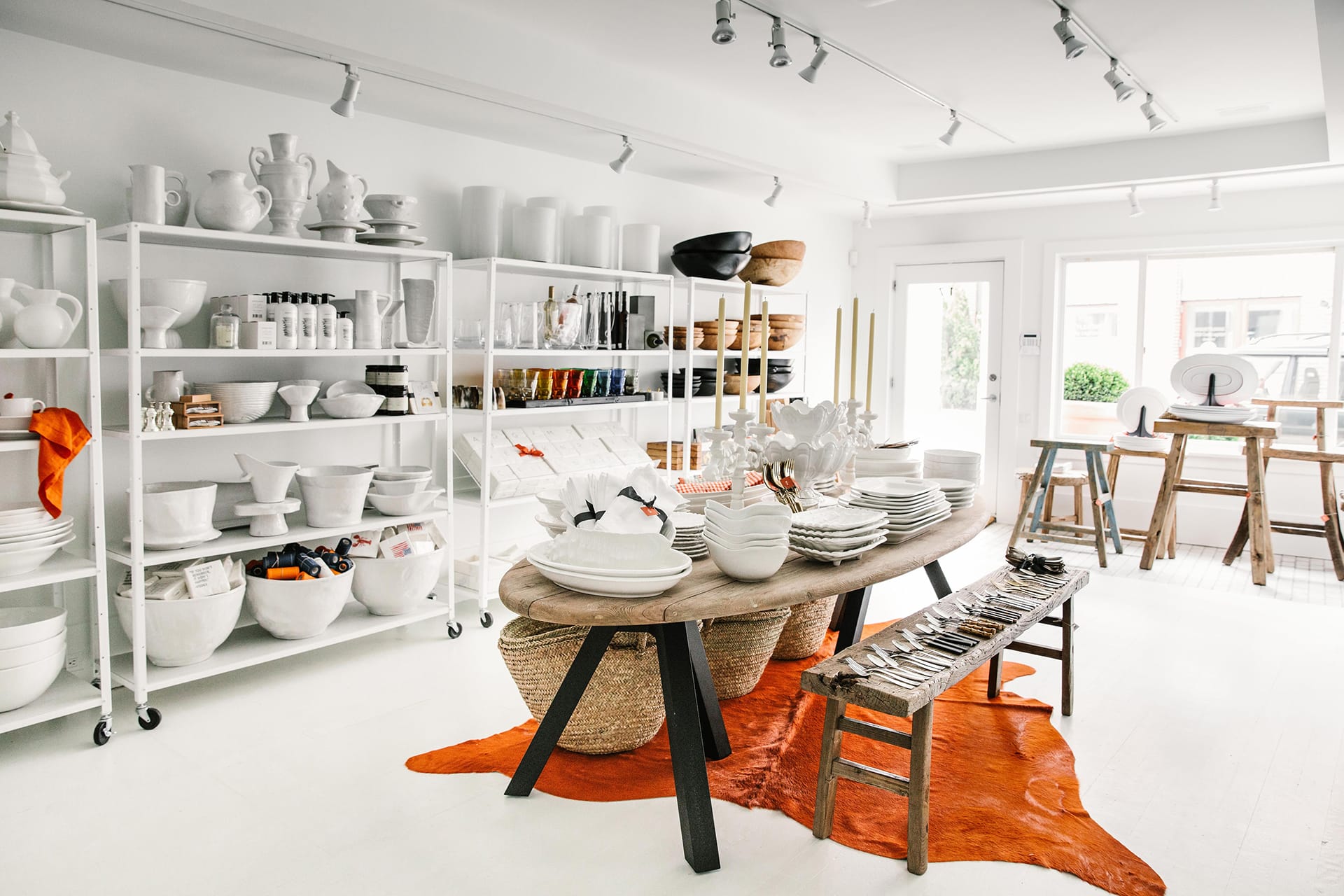 Modern kitchenware and home decor store with white shelves, artful bowls, ceramic vases, and a rustic wooden table display.