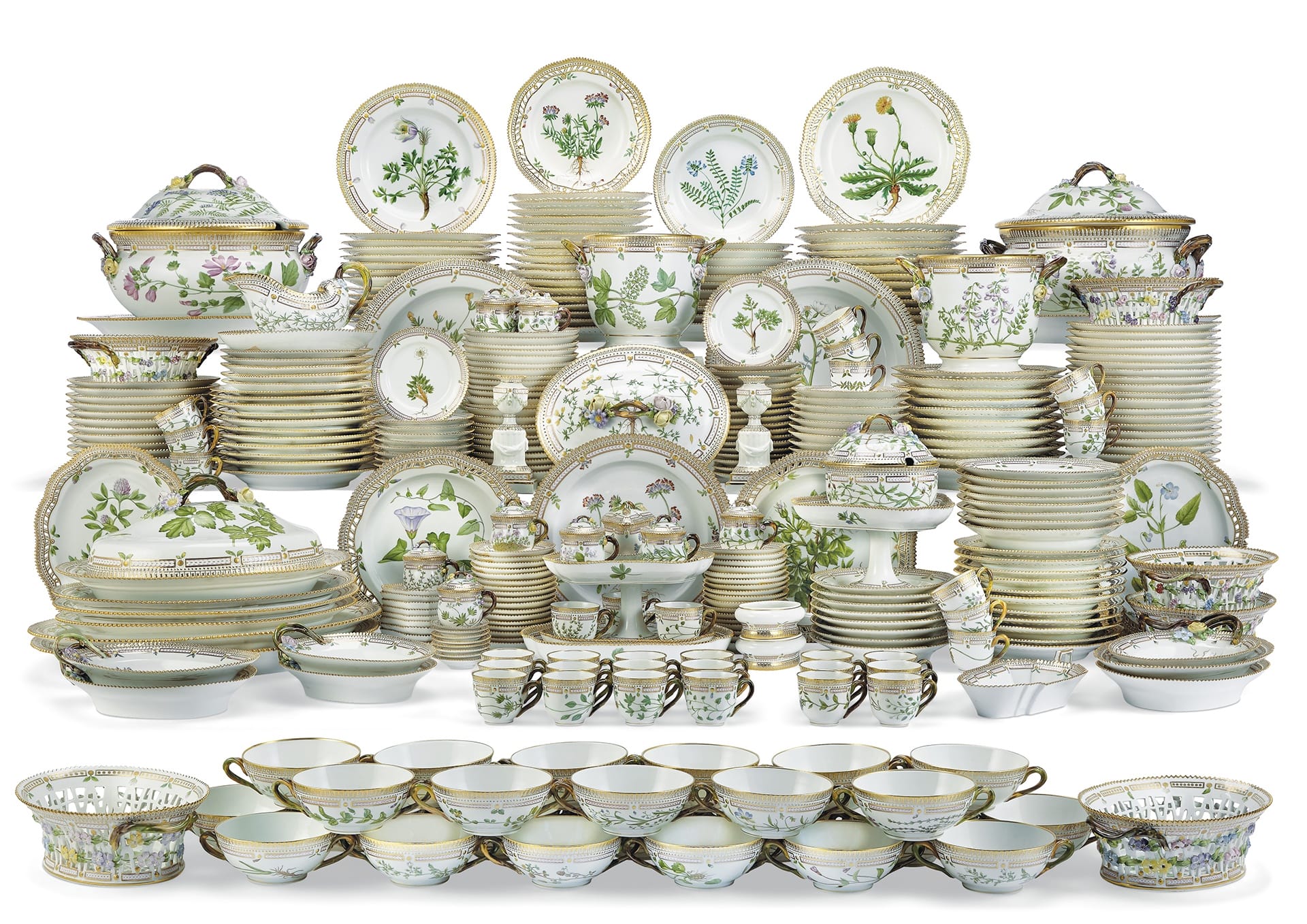 A large collection of elegant porcelain dinnerware with floral patterns, including plates, bowls, teapots, and serving dishes.