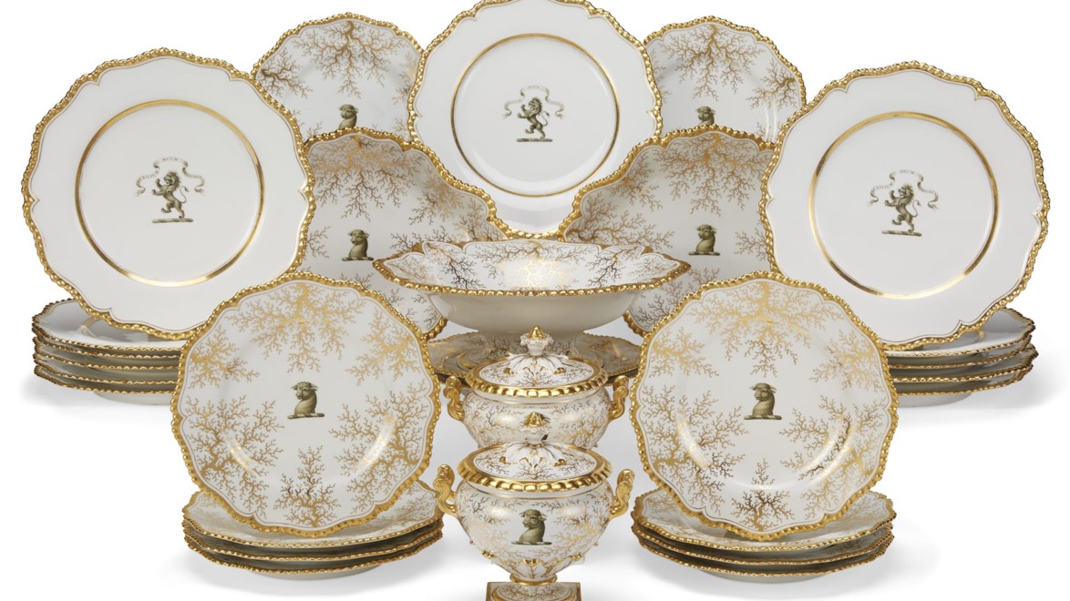 Elegant vintage dinnerware set with gold trim and intricate designs, featuring plates and ornate serving pieces.