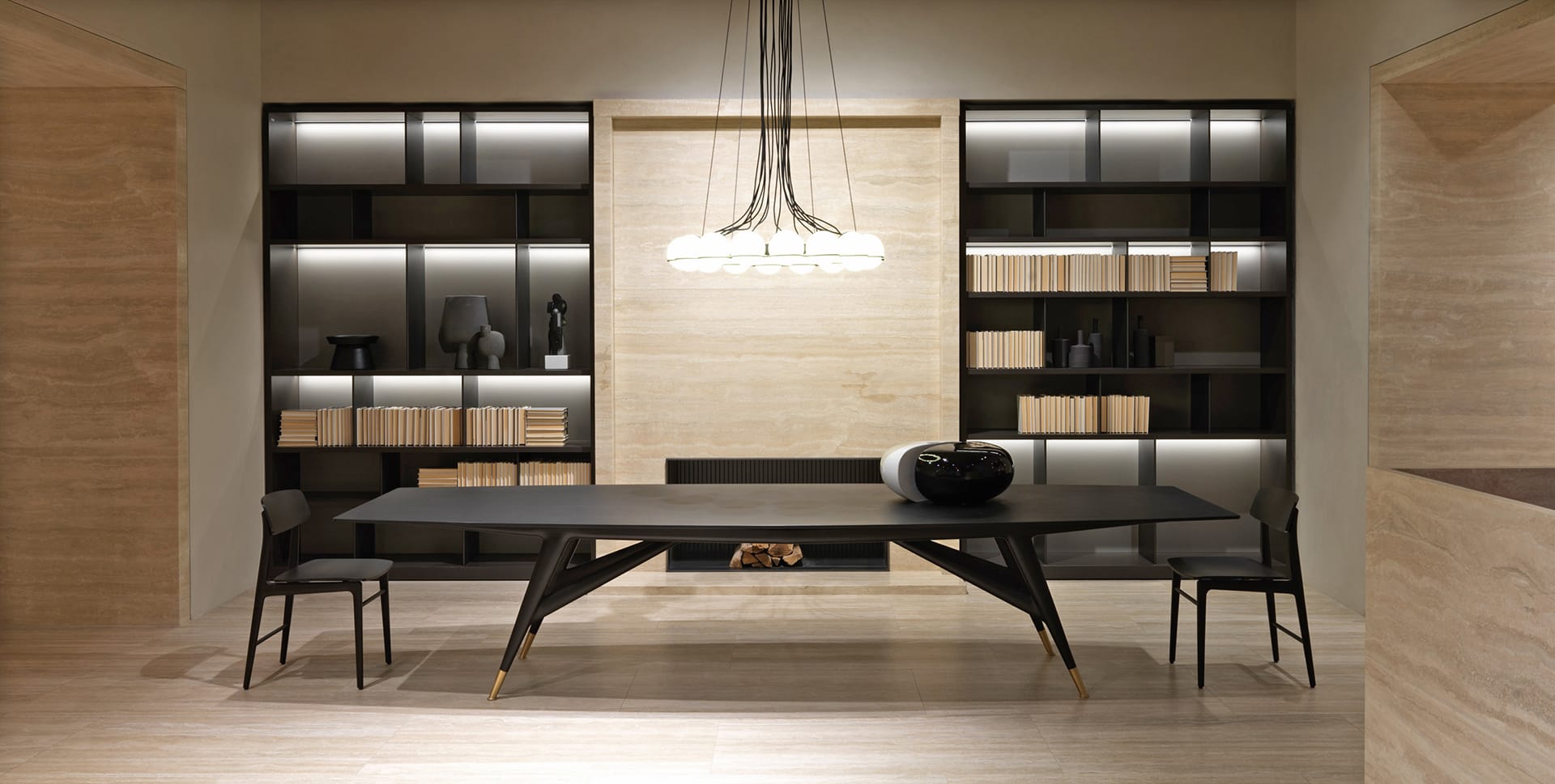Modern dining room with black table and chairs, minimalist decor, built-in shelves with books, and elegant pendant lighting.
