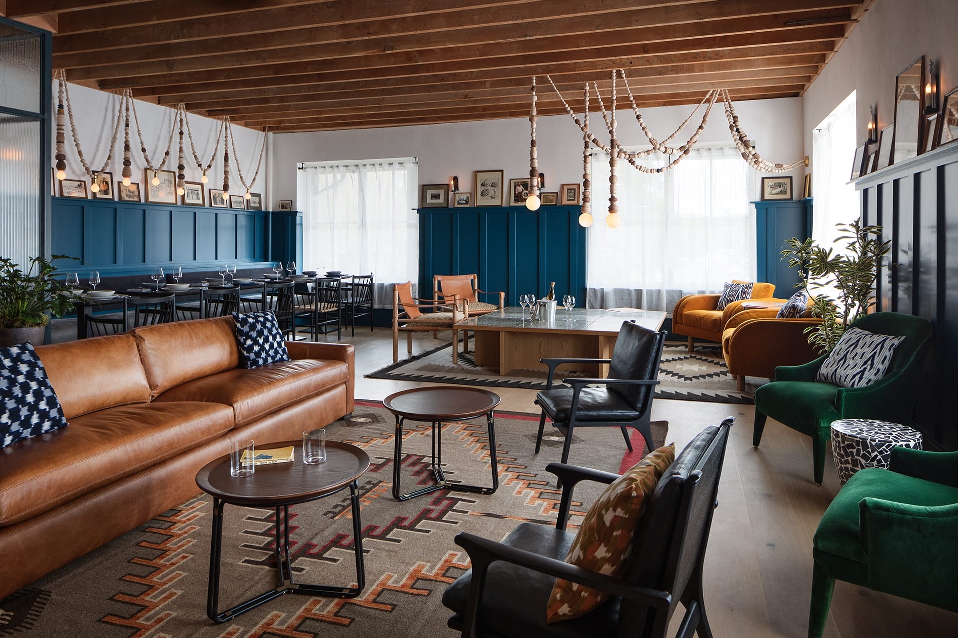 Stylish living room with leather sofas, dark wood ceiling, colorful rugs, and modern decor.