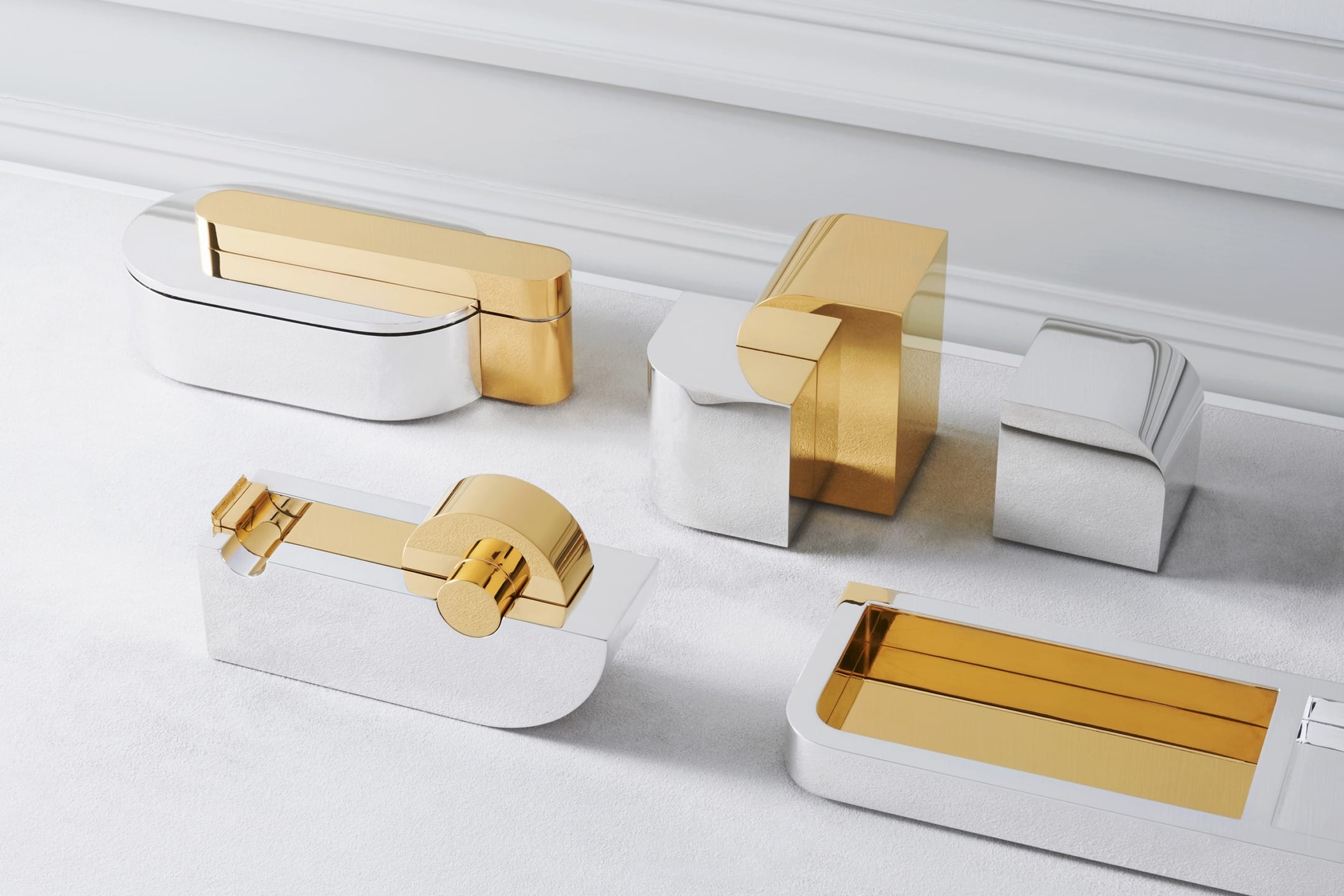Luxurious gold and silver bathroom fixtures displayed on a light surface.