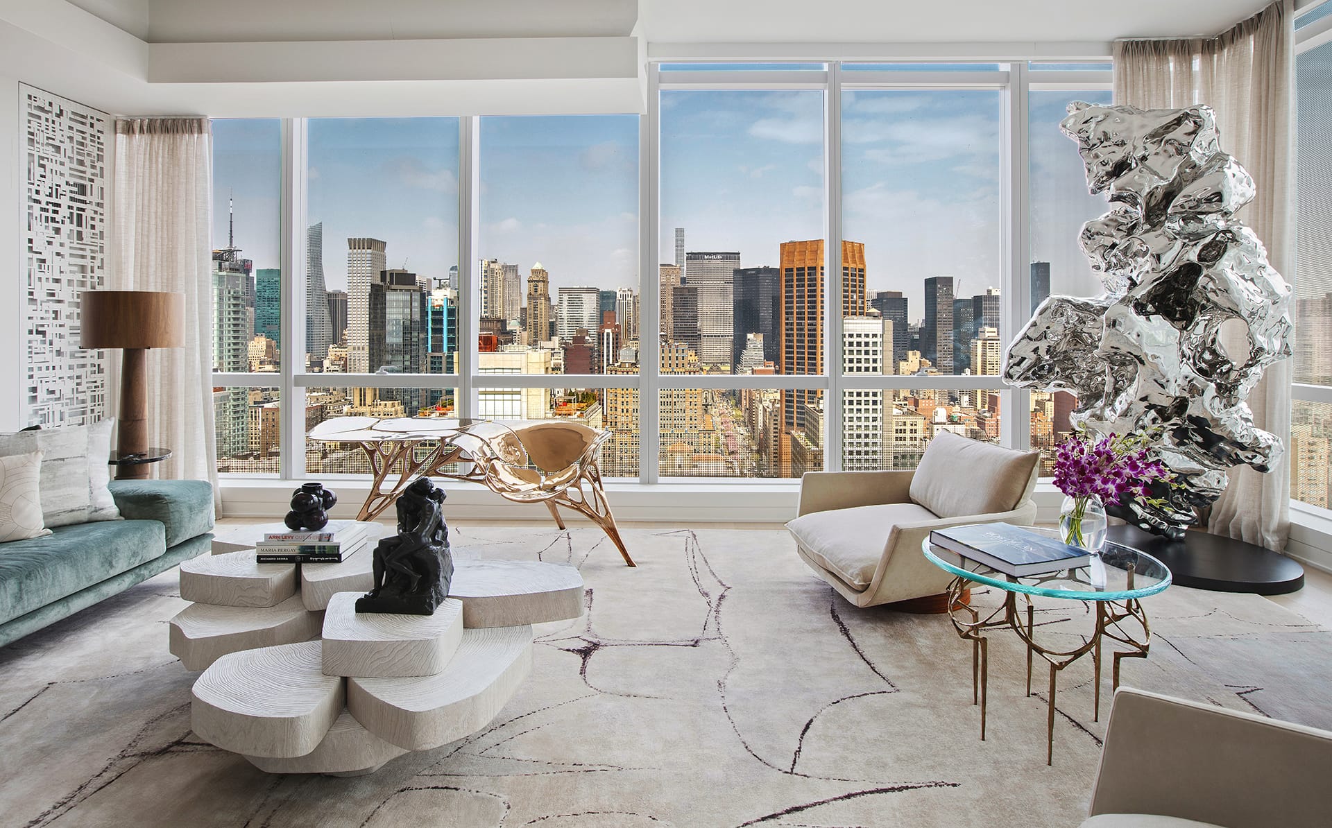 Modern living room with abstract furniture, sculptures, and large windows offering a cityscape view.