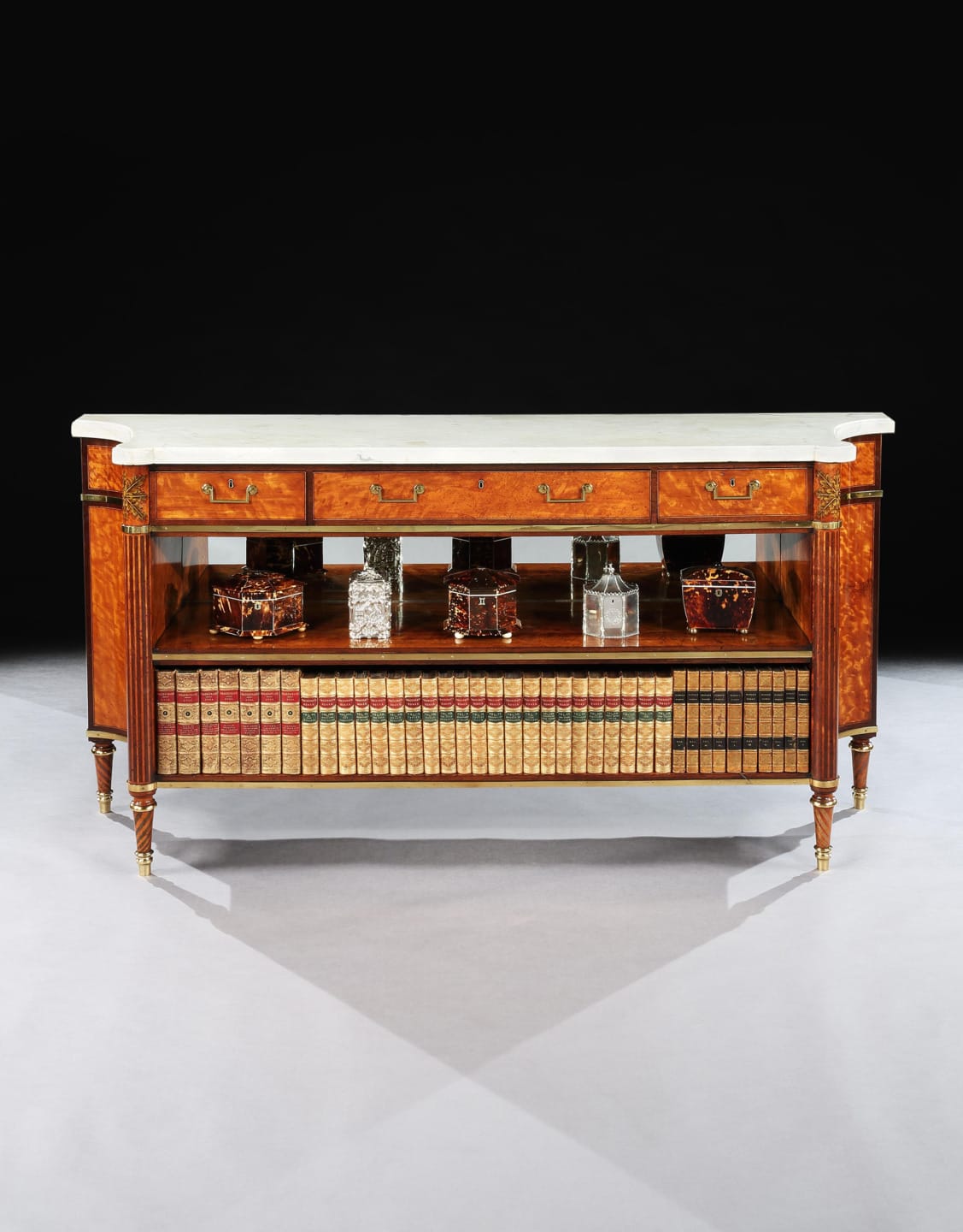 Antique wooden sideboard with marble top, featuring ornate details, books, and decorative items on shelves.