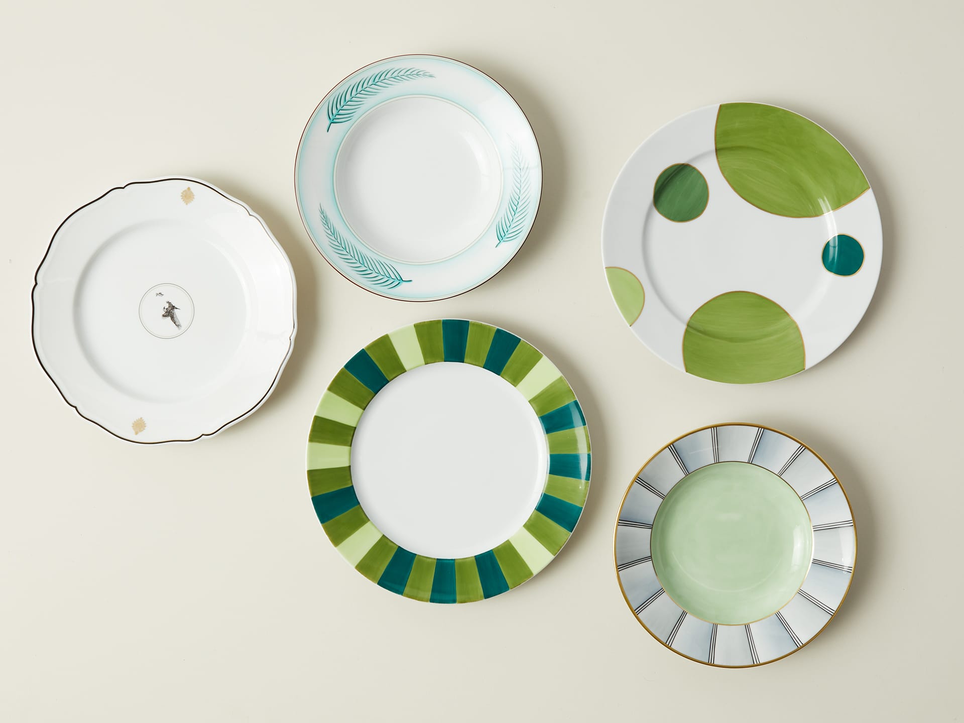 Five decorative plates with various green patterns arranged on a light background.
