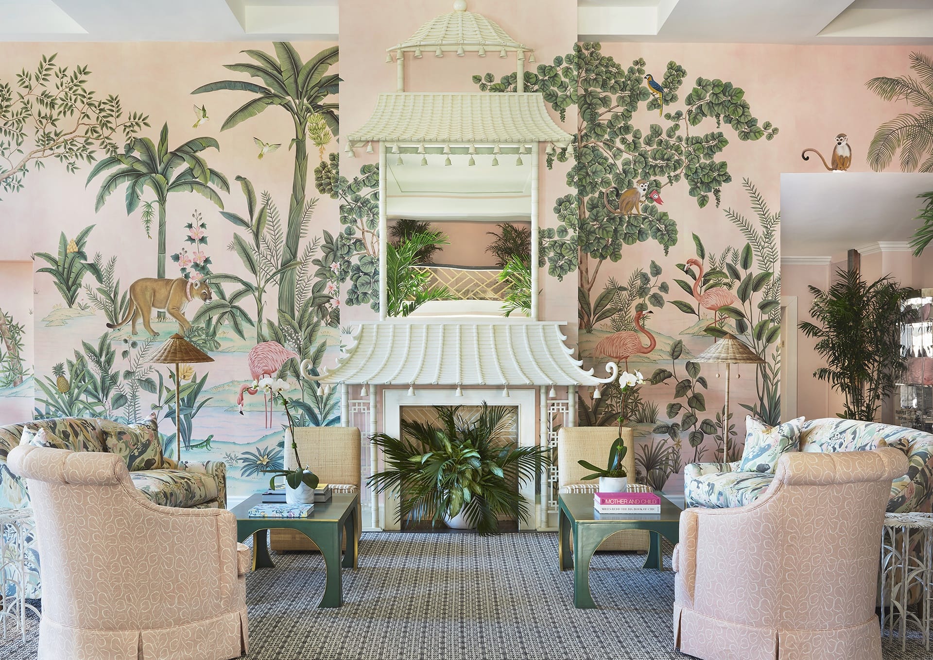 Pink-themed living room with tropical flora and fauna wall mural, elegant furniture, and a central decorative fireplace.