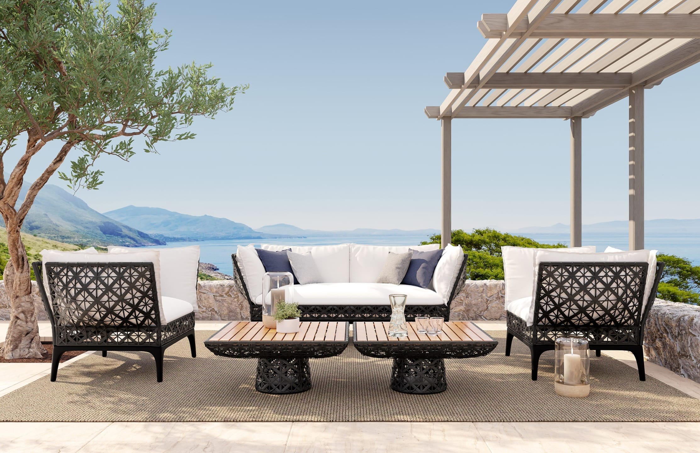 Outdoor patio furniture set with white cushions, black ornate frames, two tables, ocean view, and a pergola in the background.