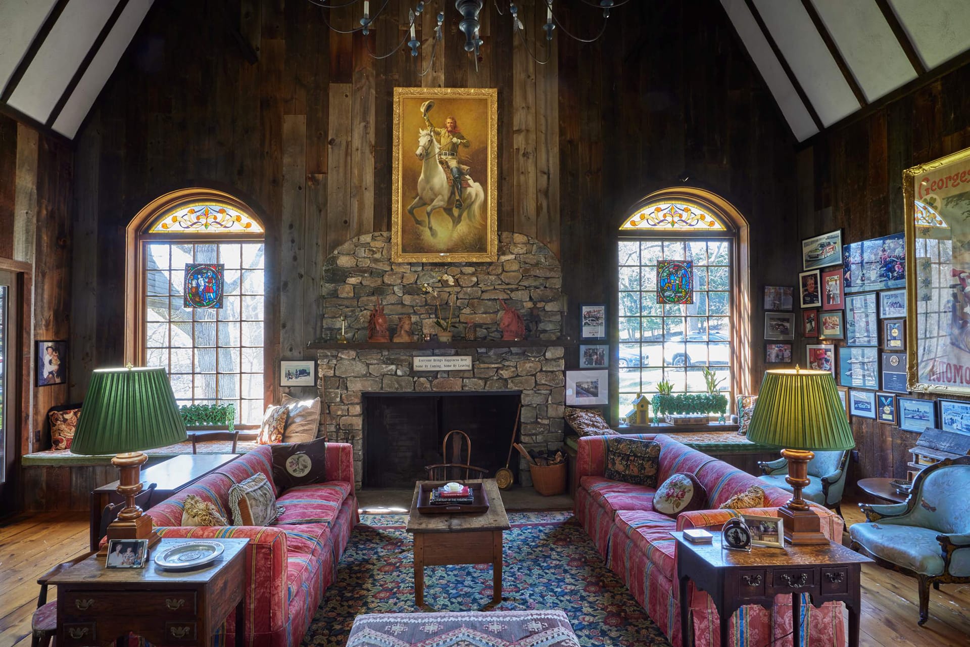 Cozy rustic living room with stone fireplace, vaulted ceiling, colorful couches, and artwork on the walls.