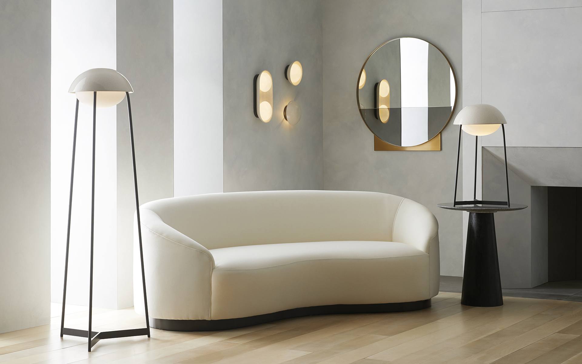 Modern living room with a curved white sofa, minimalist floor lamps, circular wall mirror, and soft ambient lighting.