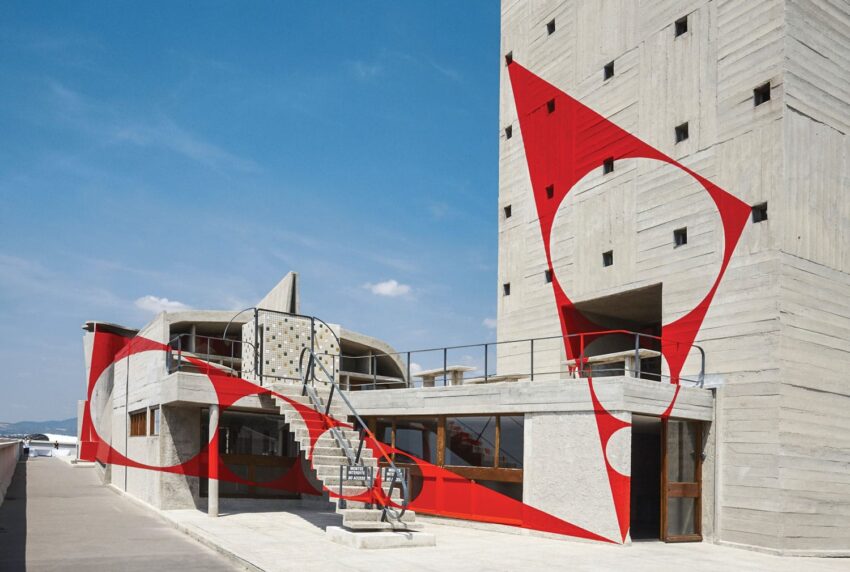 Modern architectural structure with abstract red geometric patterns on a sunny day.